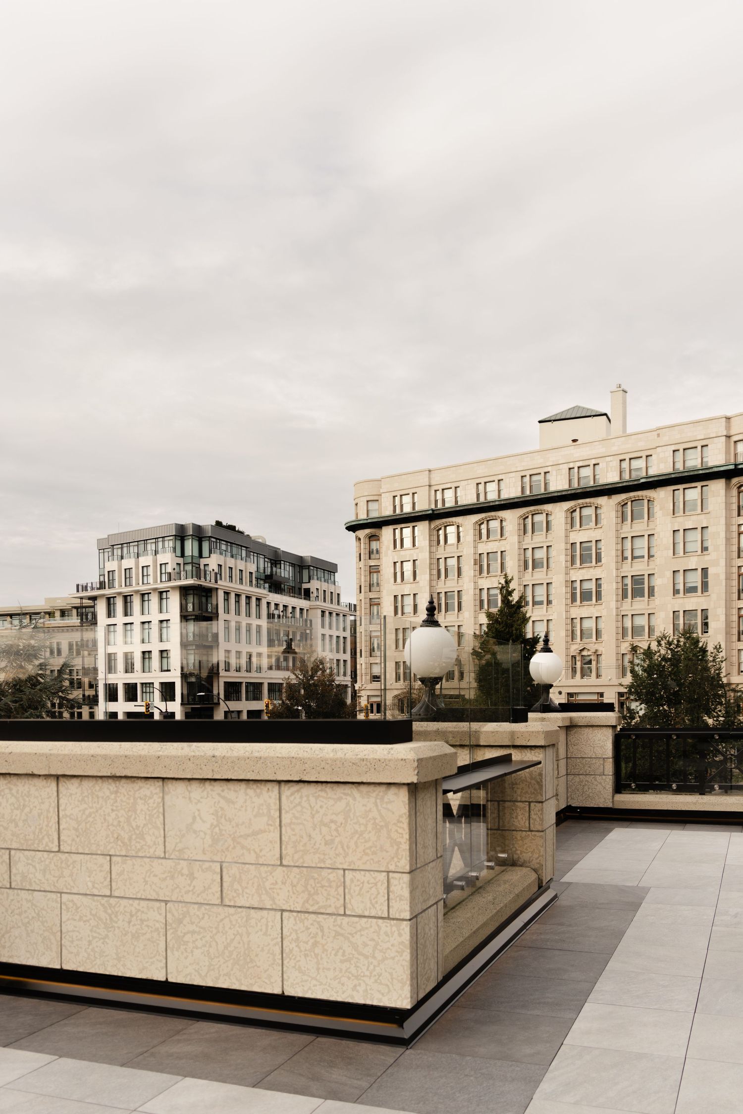 Urban rooftop terrace with stone walls and city buildings in background on overcast day.