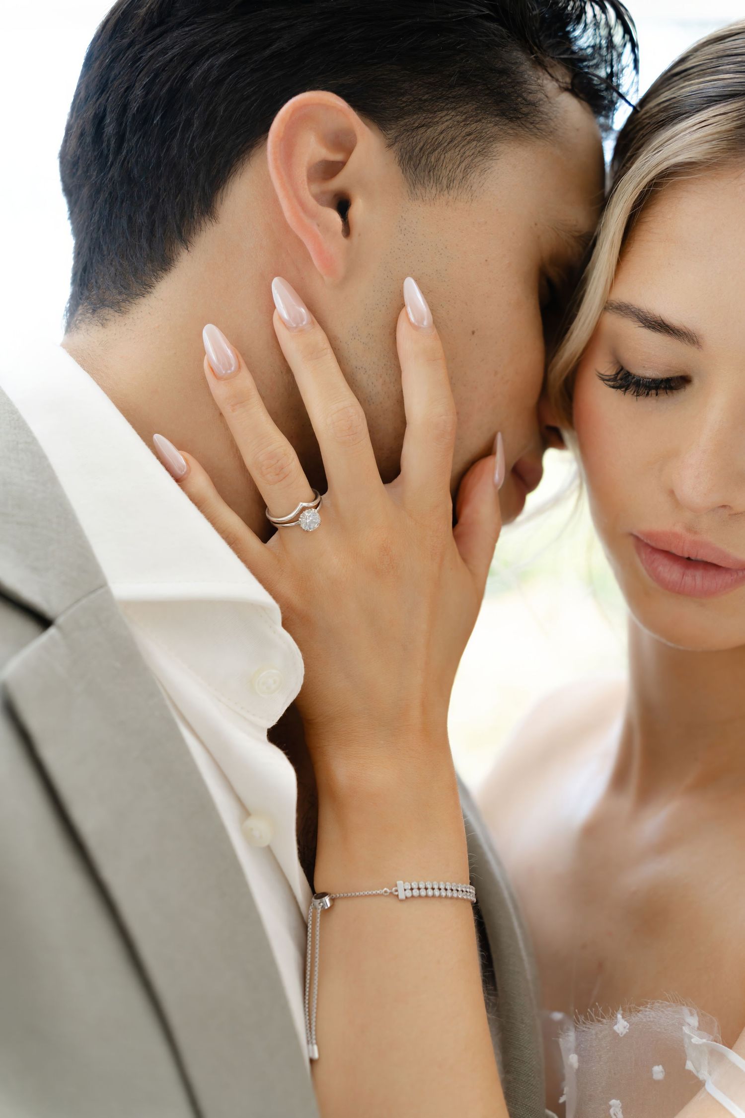 Close-up engagement photo showing a diamond ring and manicured nails during intimate moment.