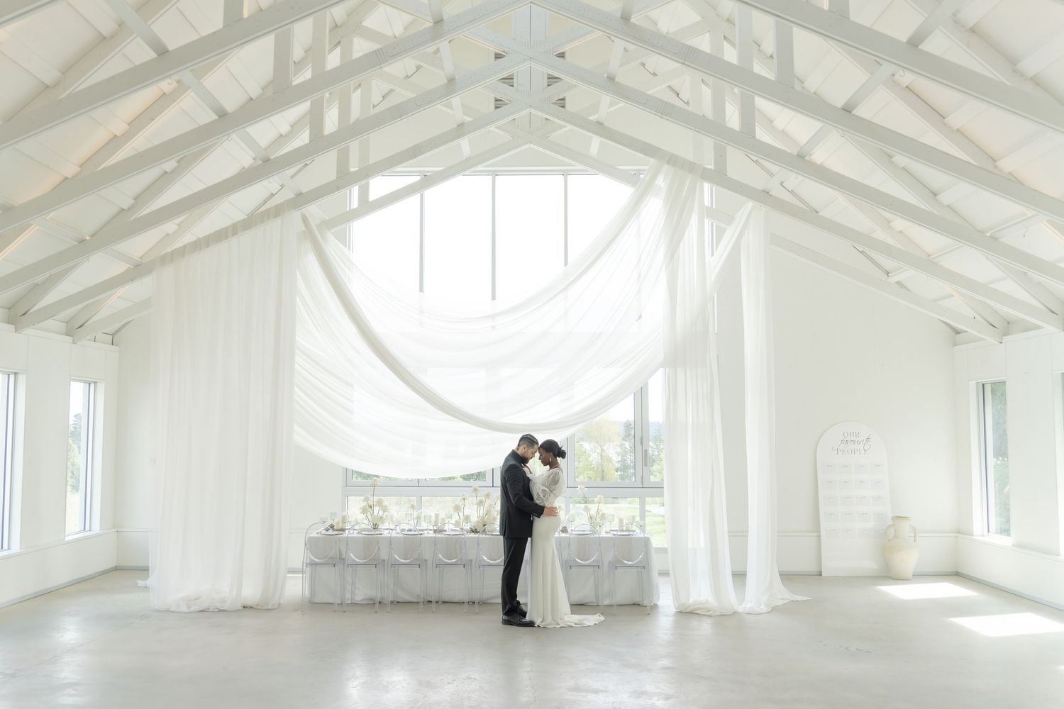 Modern white wedding venue interior with vaulted ceiling and natural light.
