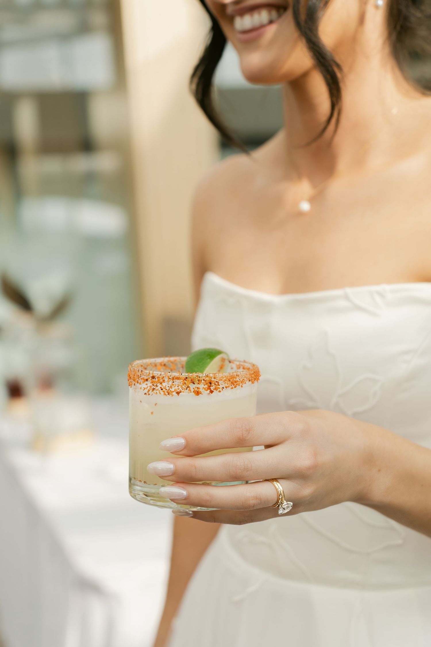 Close-up of hands holding cocktails at an elegant wedding reception.