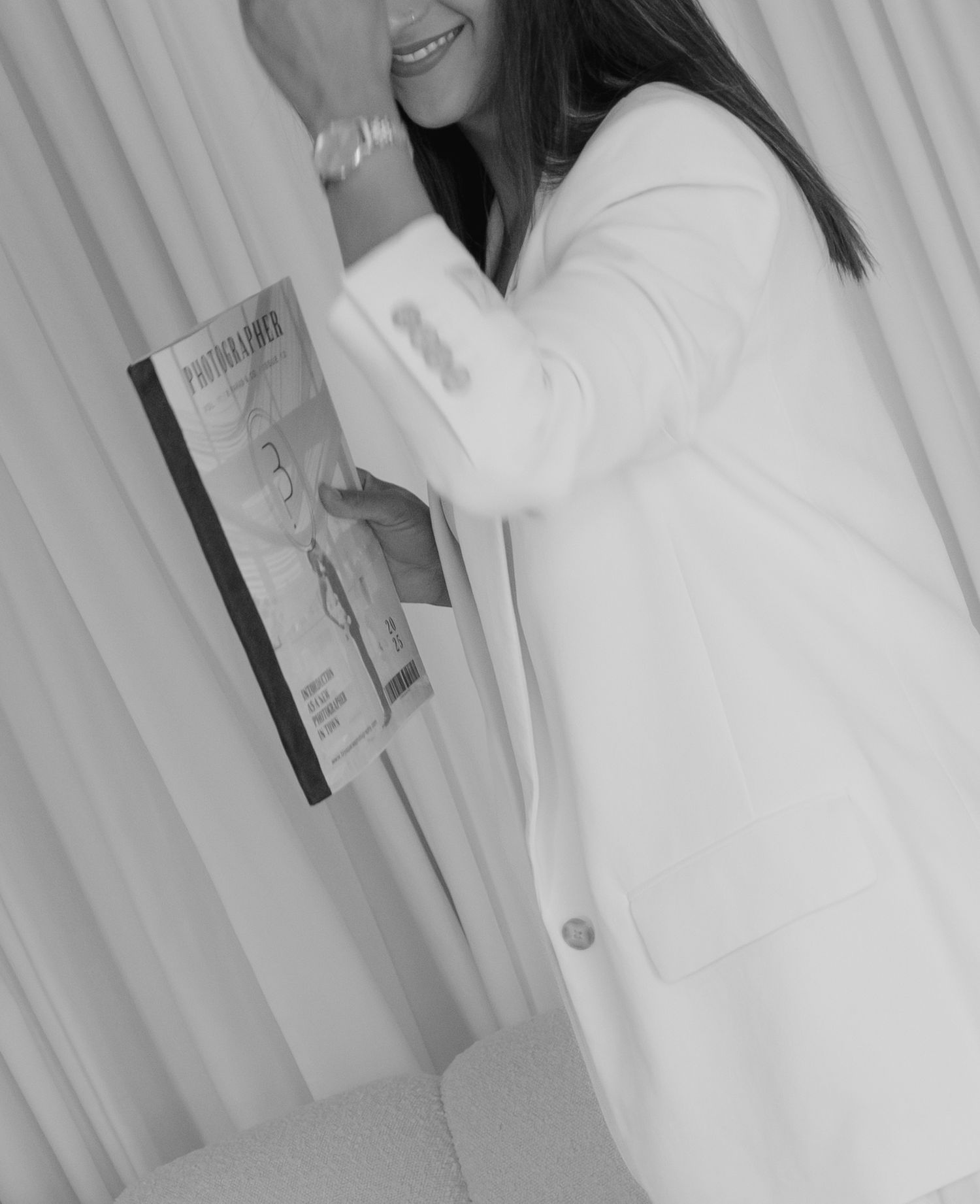 Side view of person in white jacket holding book against light curtains.