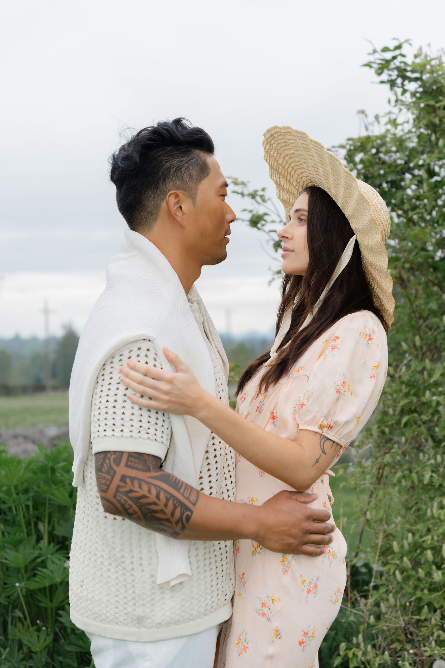 Romantic couple in white and peach outfits embracing in a meadow.