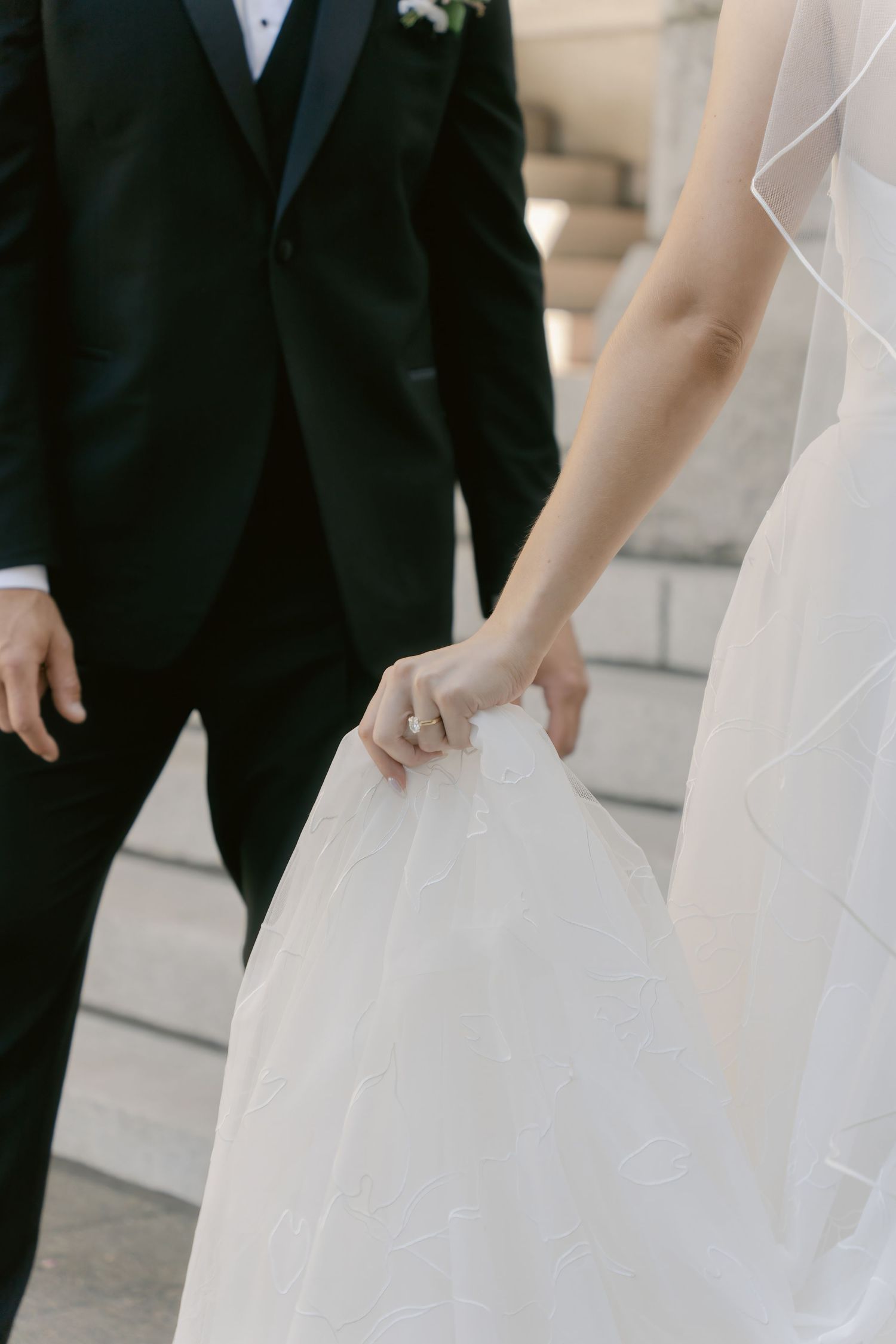 A bride in a white strapless gown stands next to a groom in a black tuxedo on their wedding day.