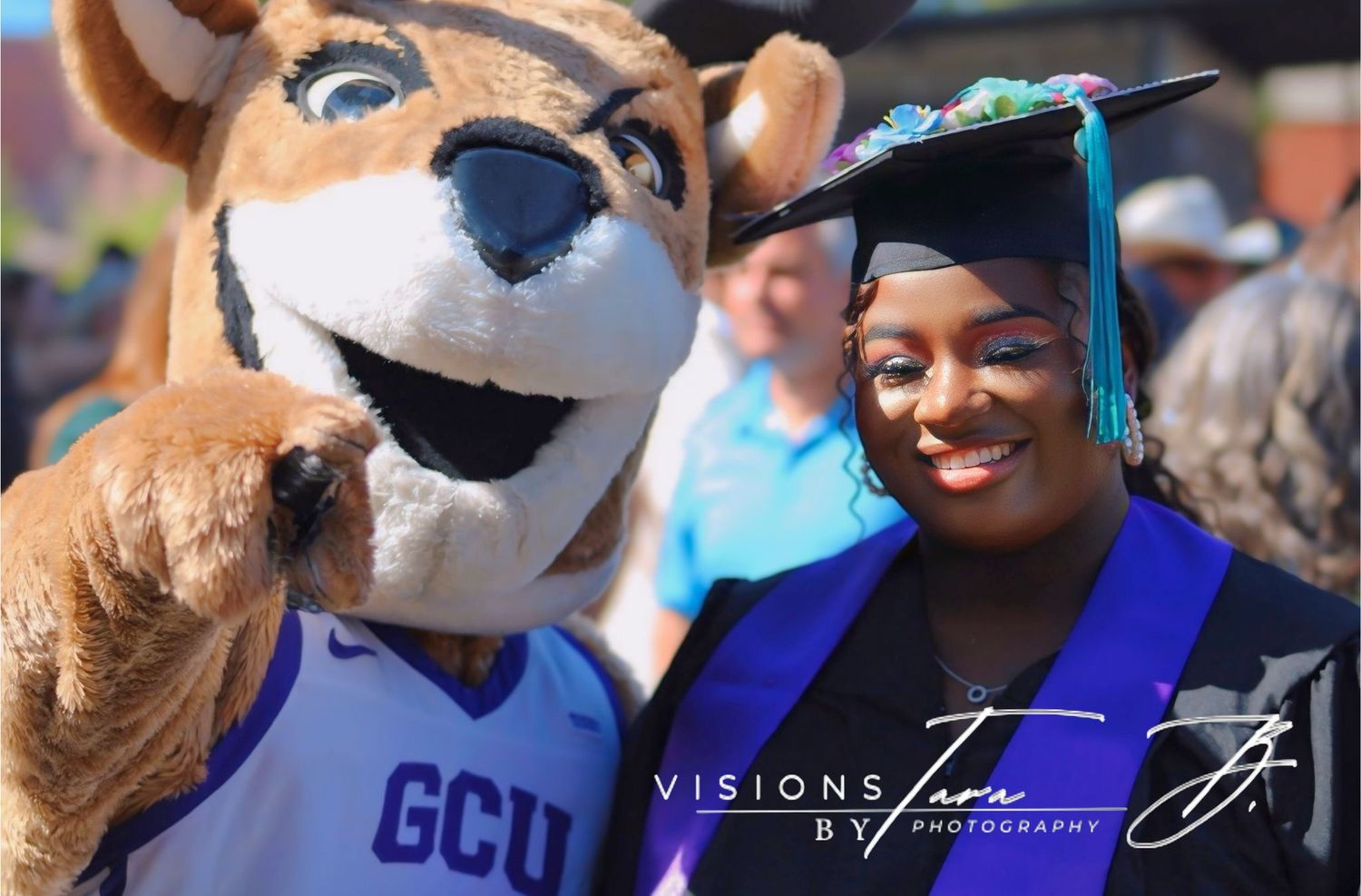 Graduate smiling next to the GCU mascot during commencement festivities, capturing a joyful celebration moment.