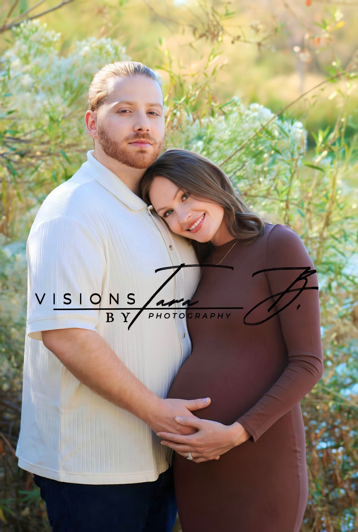 Expecting couple embracing gently in nature, hands on the baby bump as they share a quiet, loving maternity moment.
