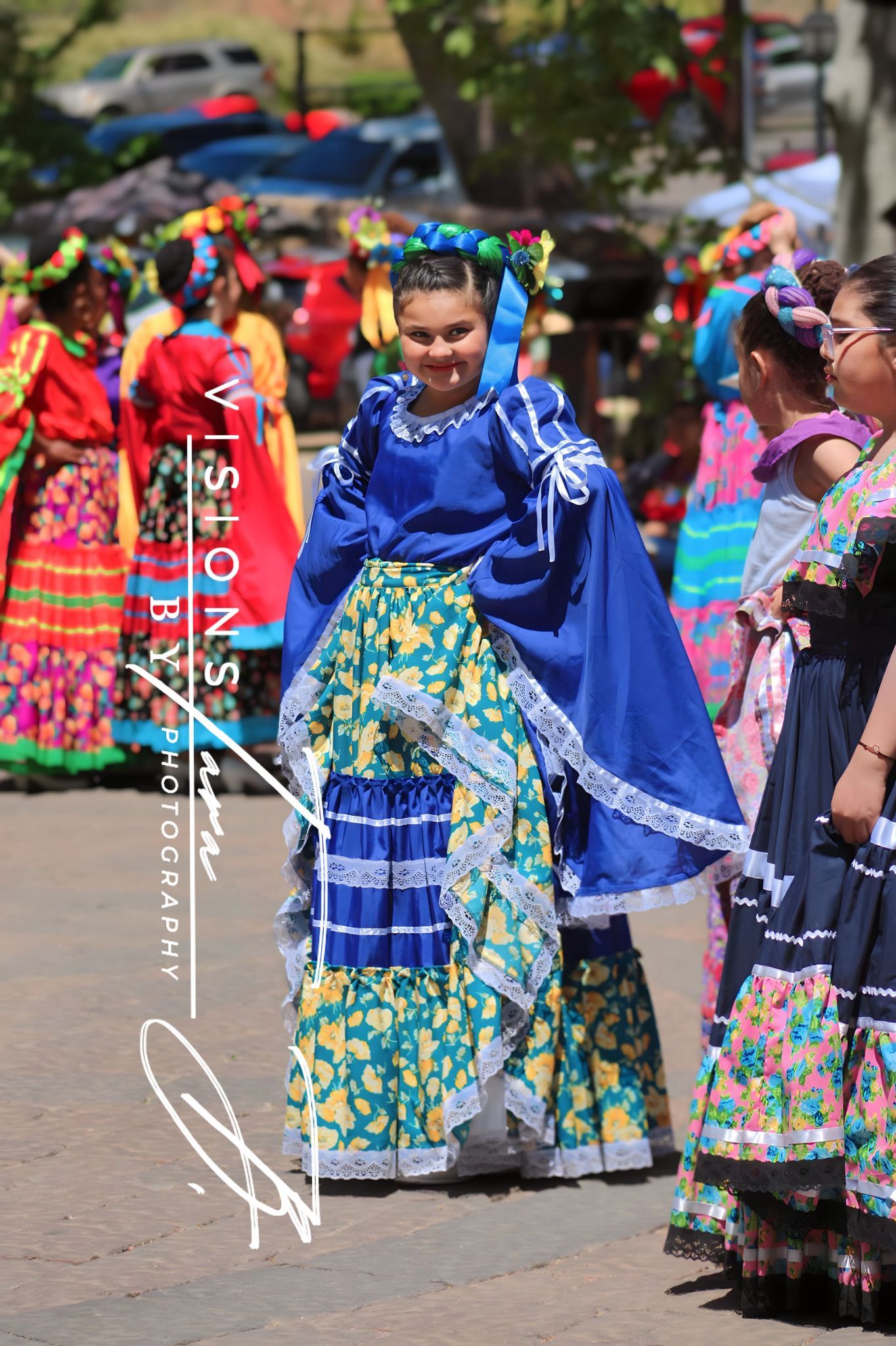 Young dancer smiling brightly in a colorful traditional dress during a lively cultural celebration.