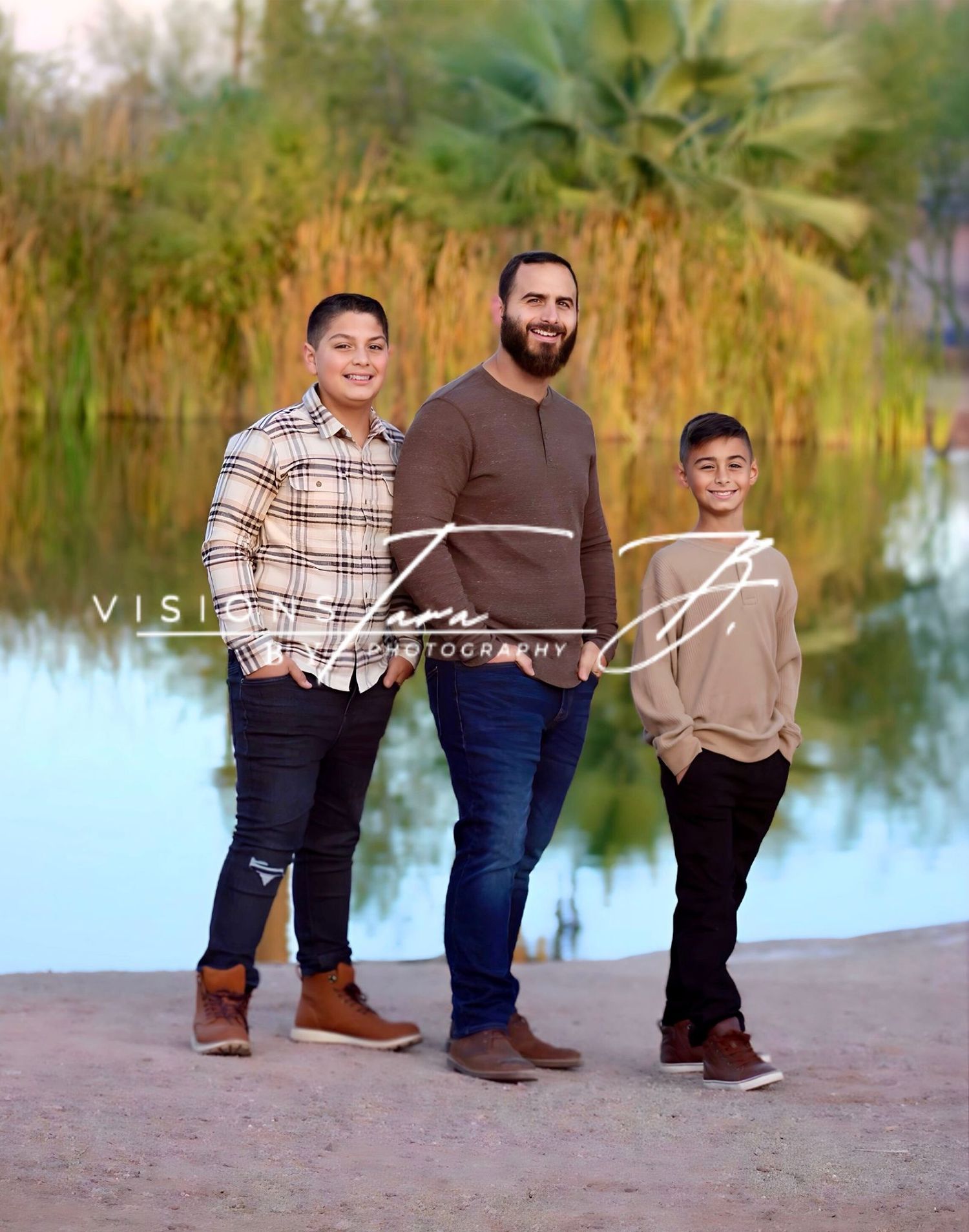 Three generations standing together by a calm lakeside, smiling warmly during a family portrait in soft natural light.