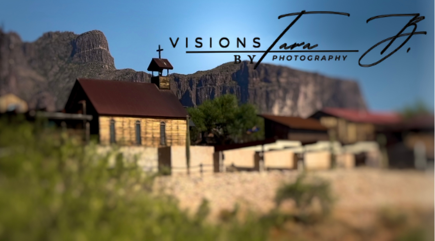 Old western-style buildings beneath a clear blue sky, with mountains in the distance.