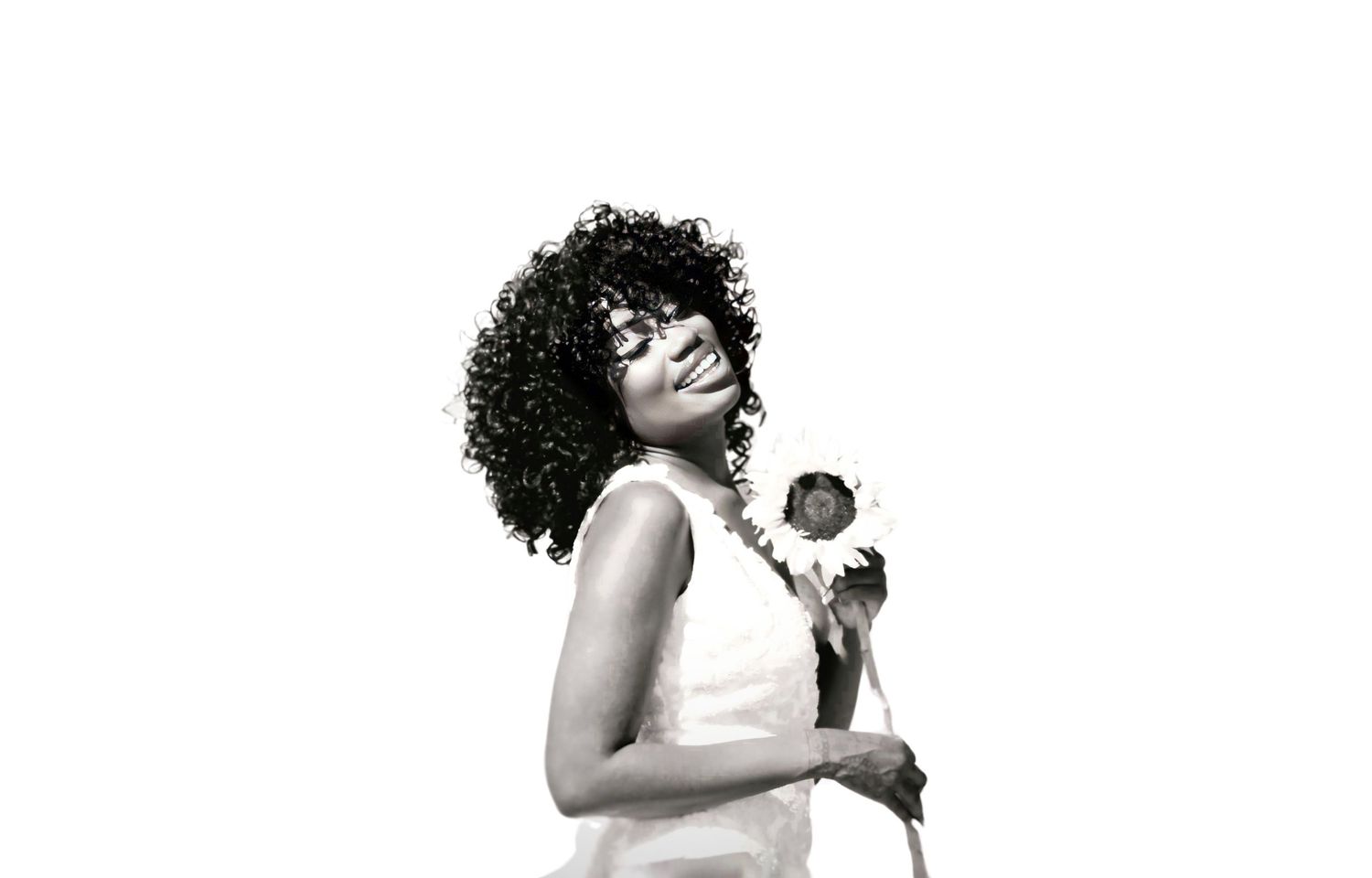 Black and white artistic portrait showing person with natural curls holding sunflower.