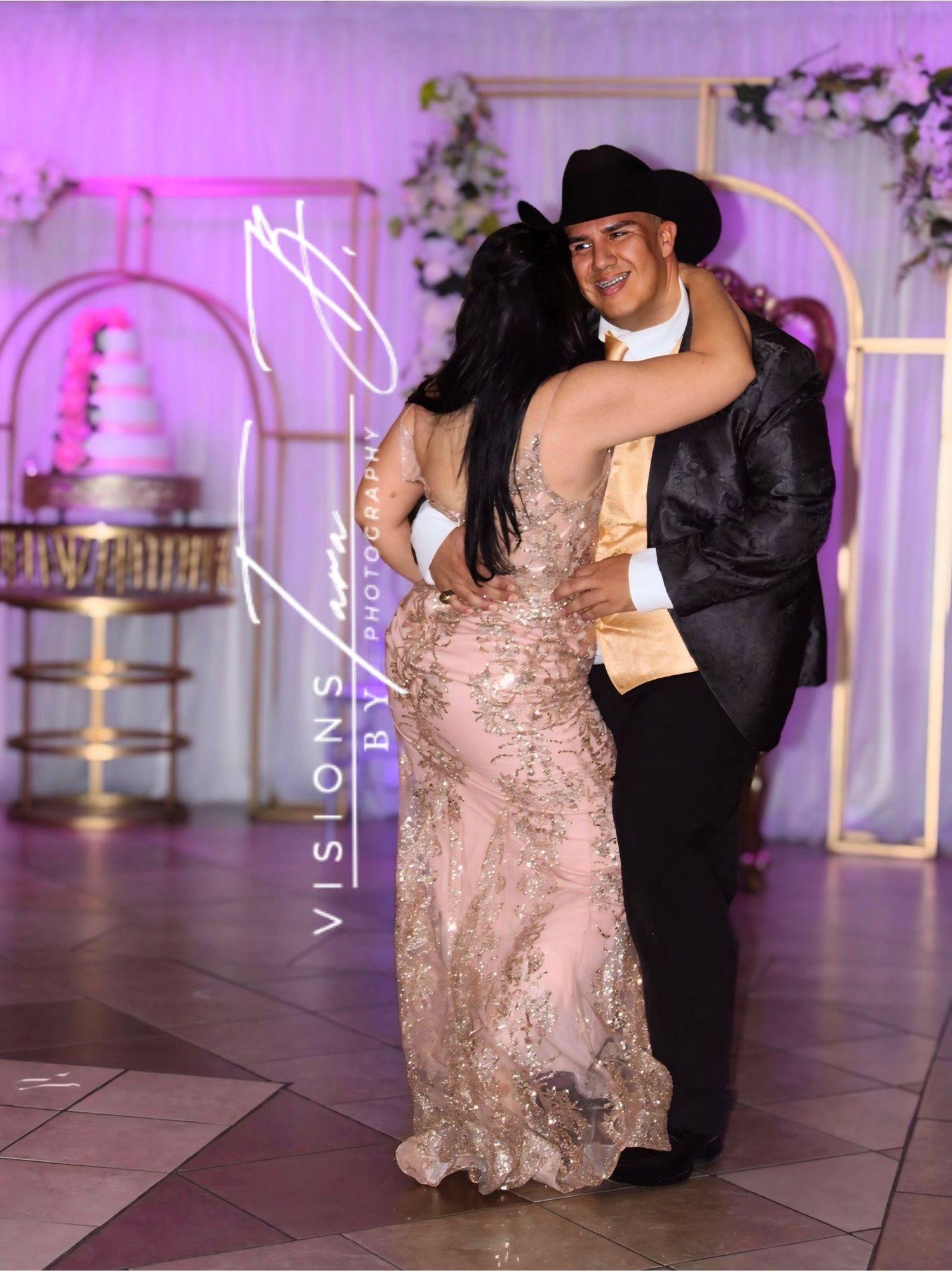 Parents dancing under warm golden lighting at a celebration, smiling as they share a joyful moment on the dance floor.