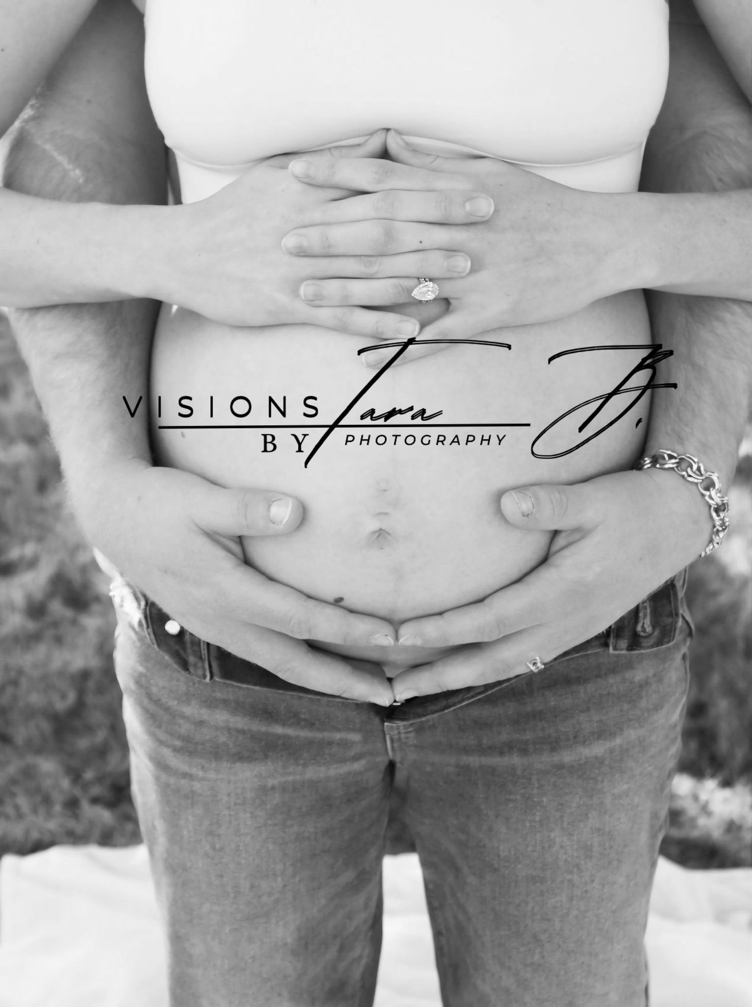 Black-and-white photo of hands gently cradling a baby bump, showing a soft and intimate maternity moment.