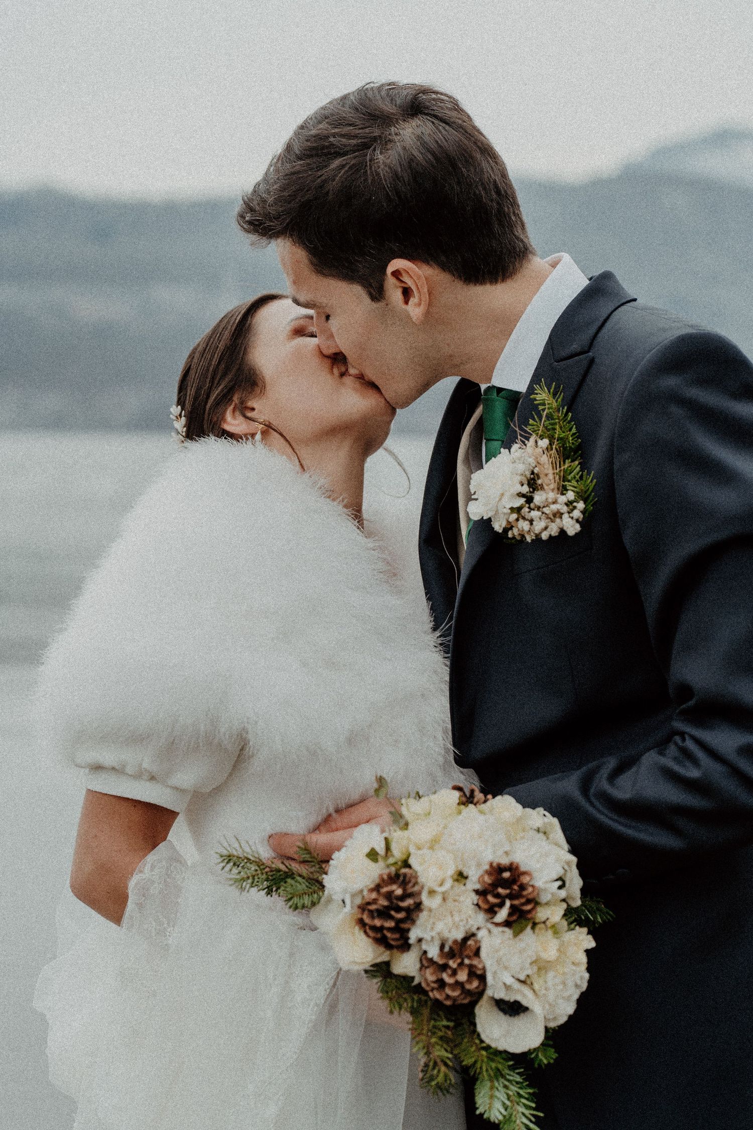 Mariés s'embrassant, bouquet d'hiver aux pommes de pin Annecy