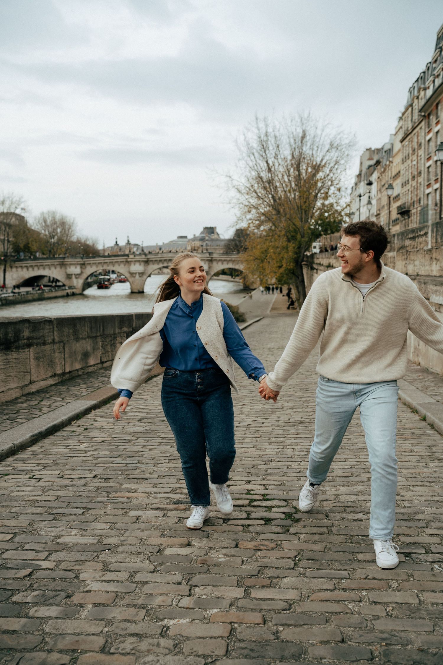 Couple marchant main dans la main sur un pont pavé