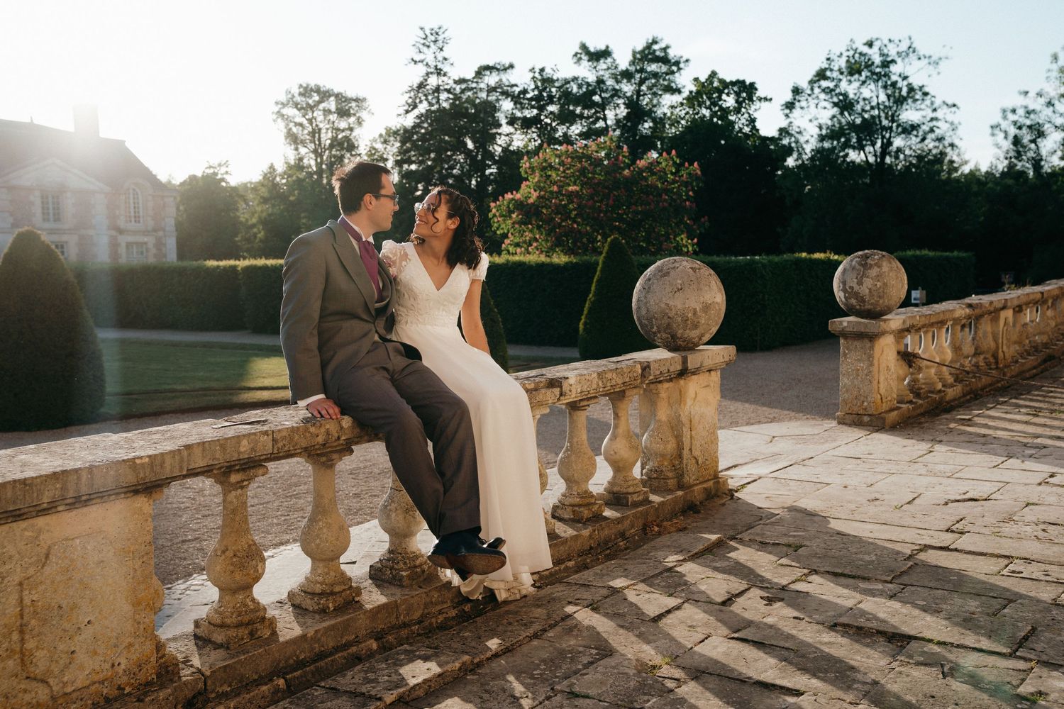Mariés assis sur une balustrade en pierre, lumière dorée
