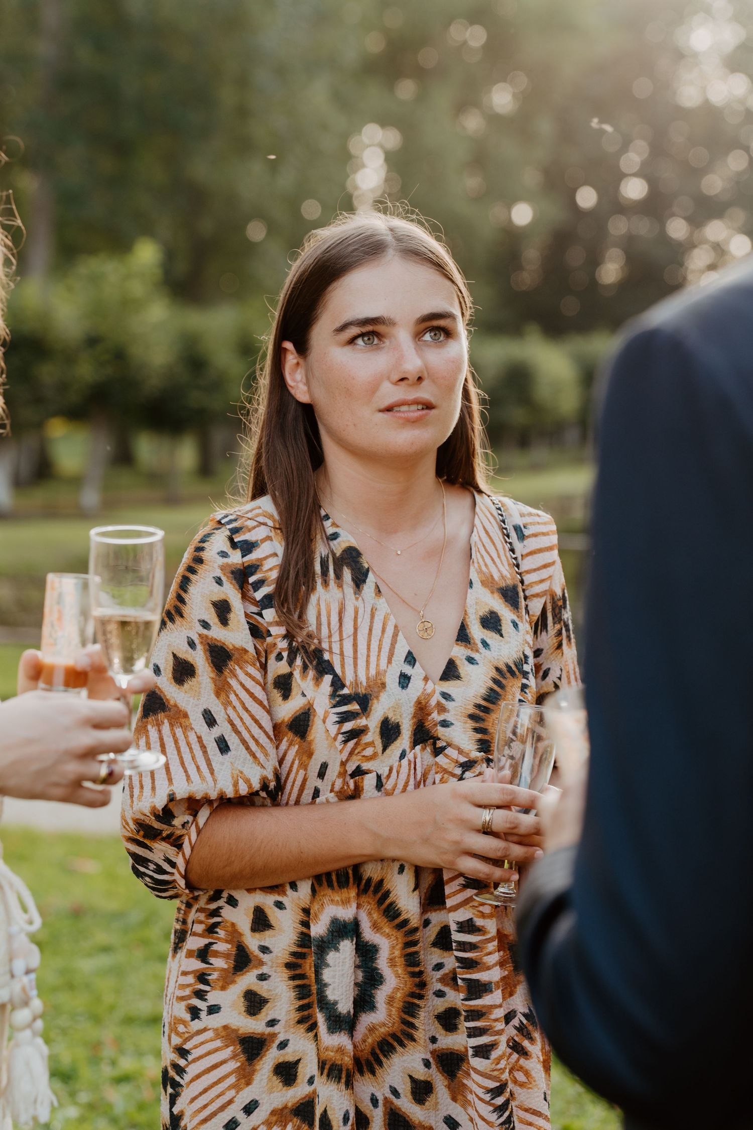 Invitée en robe imprimée savourant une coupe de champagne pendant le cocktail