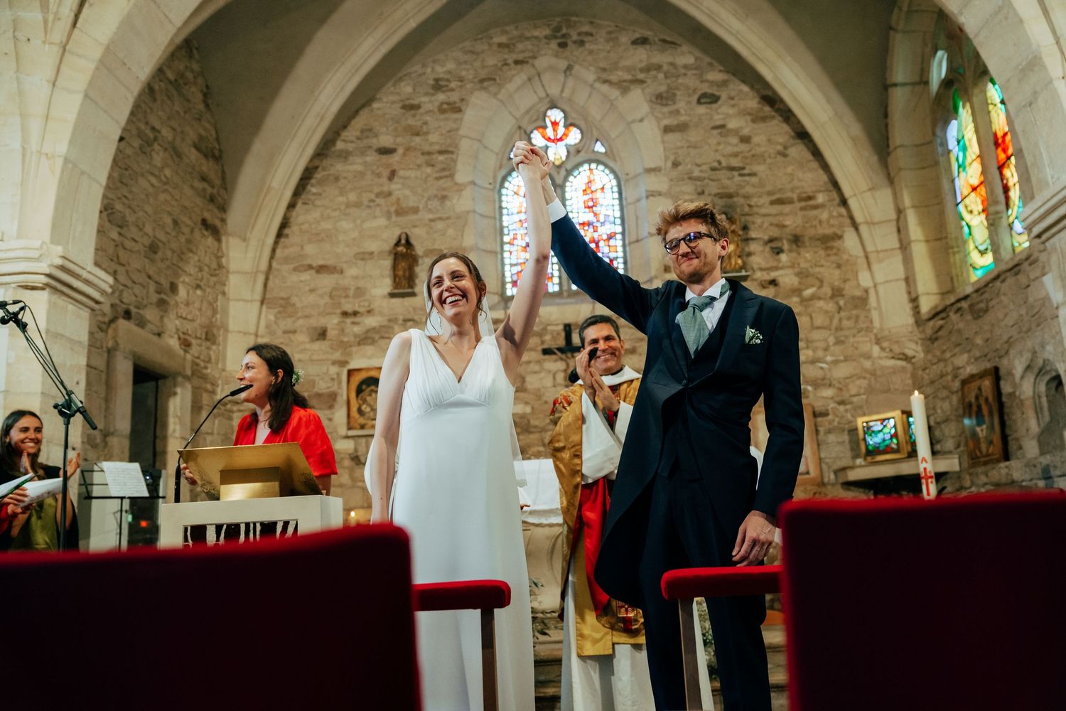 Mariés levant les mains en signe de joie à l'église