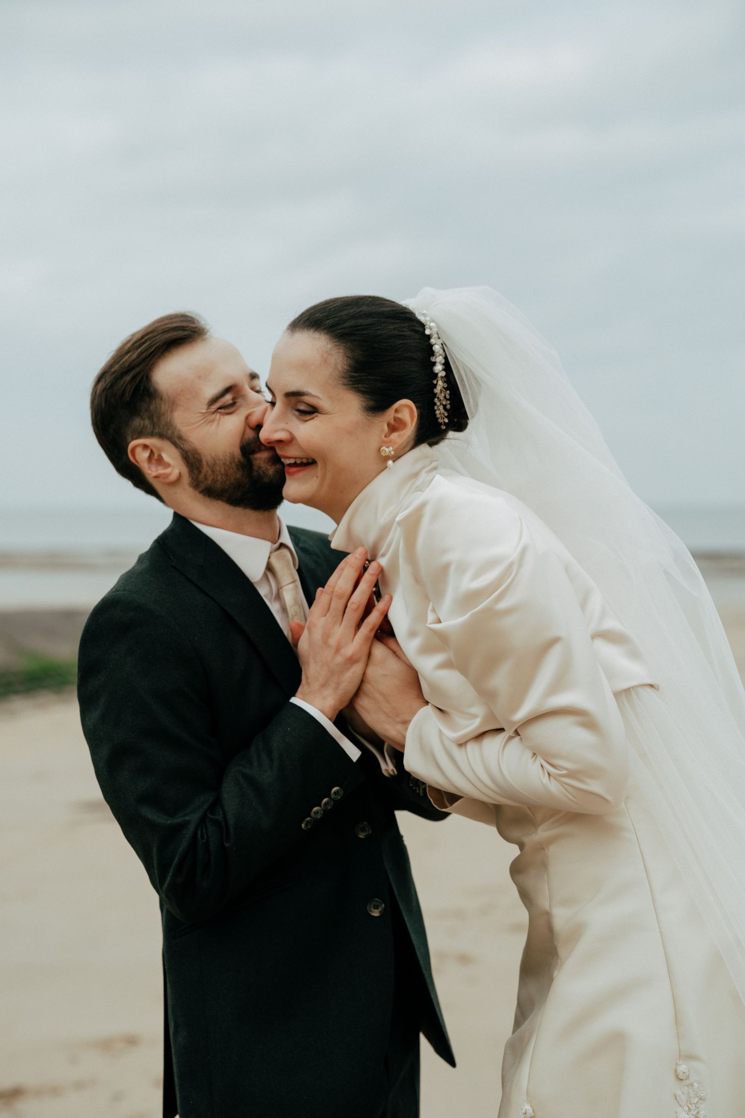 Mariée sur une plage, bouquet à la main, robe au vent Mariage d'hiver