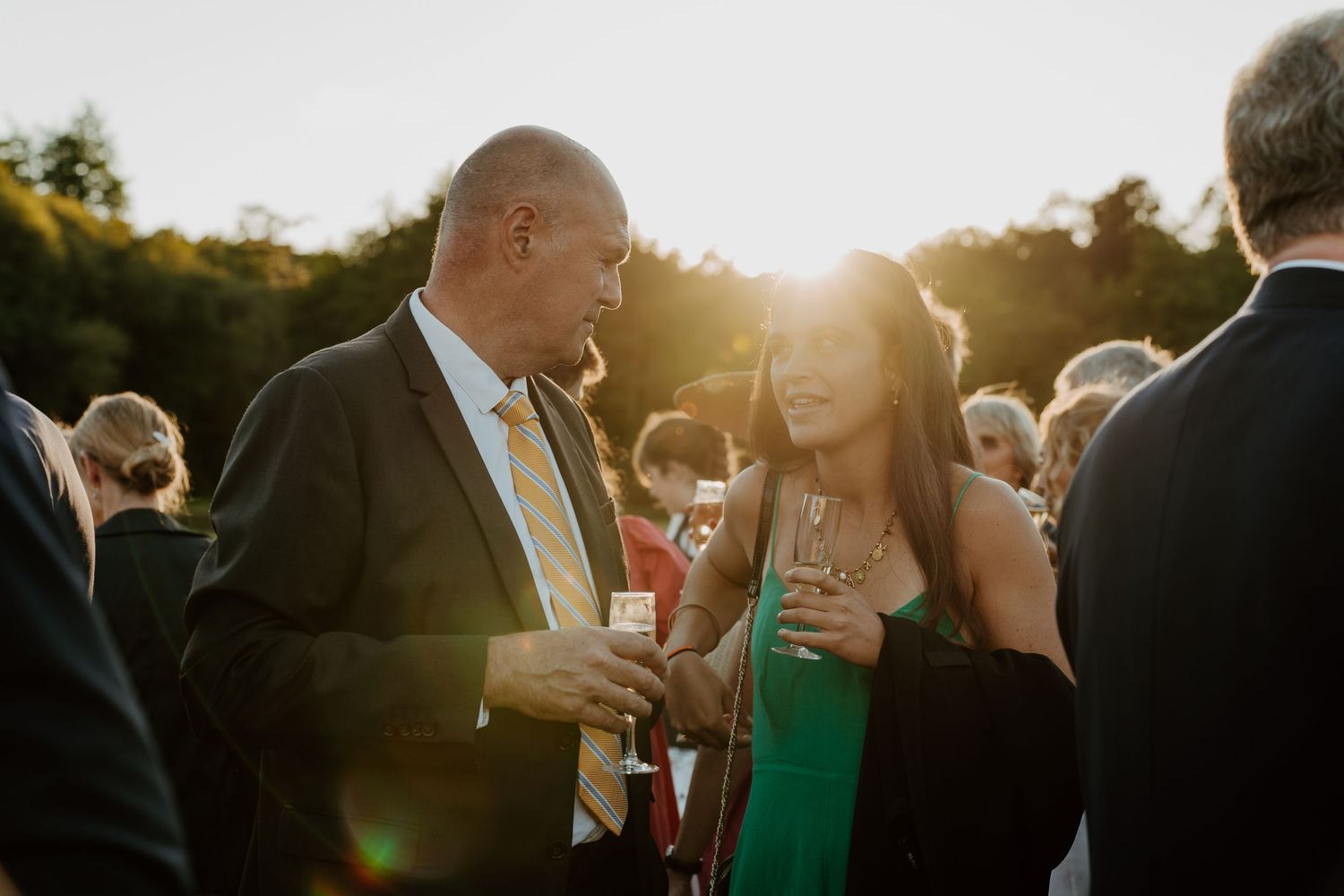 Couple d'invités complices à la lumière dorée du coucher de soleil pendant le cocktail