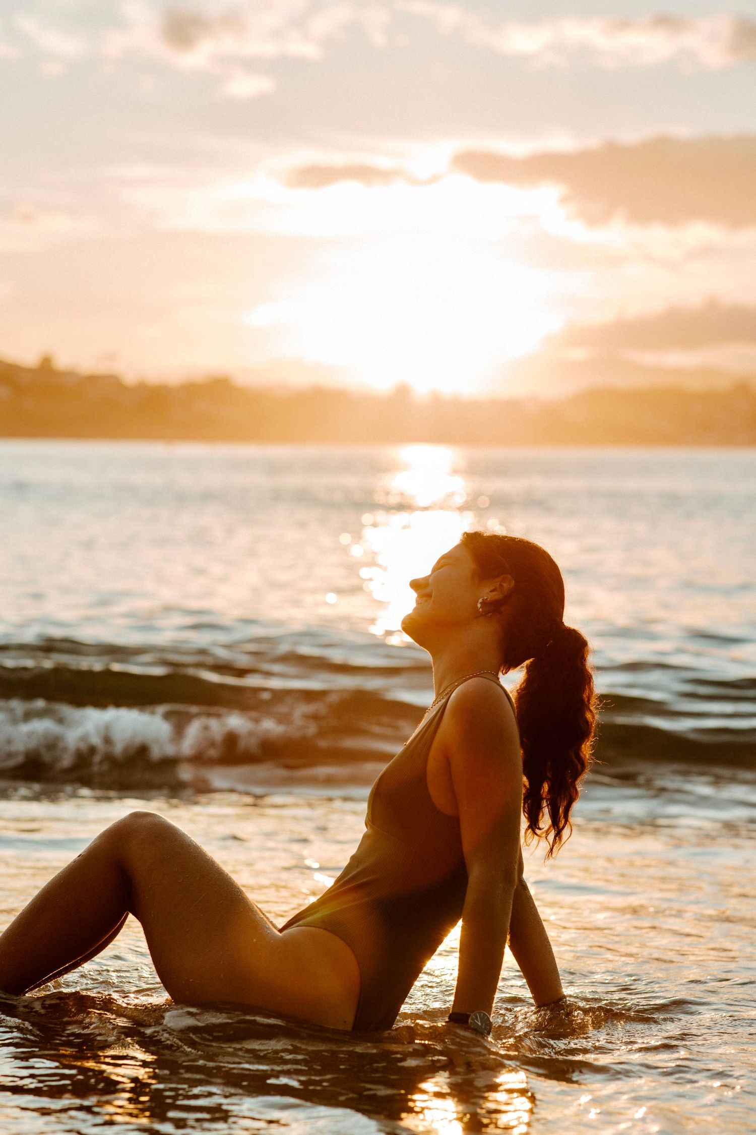 Femme assise dans l'eau au coucher du soleil