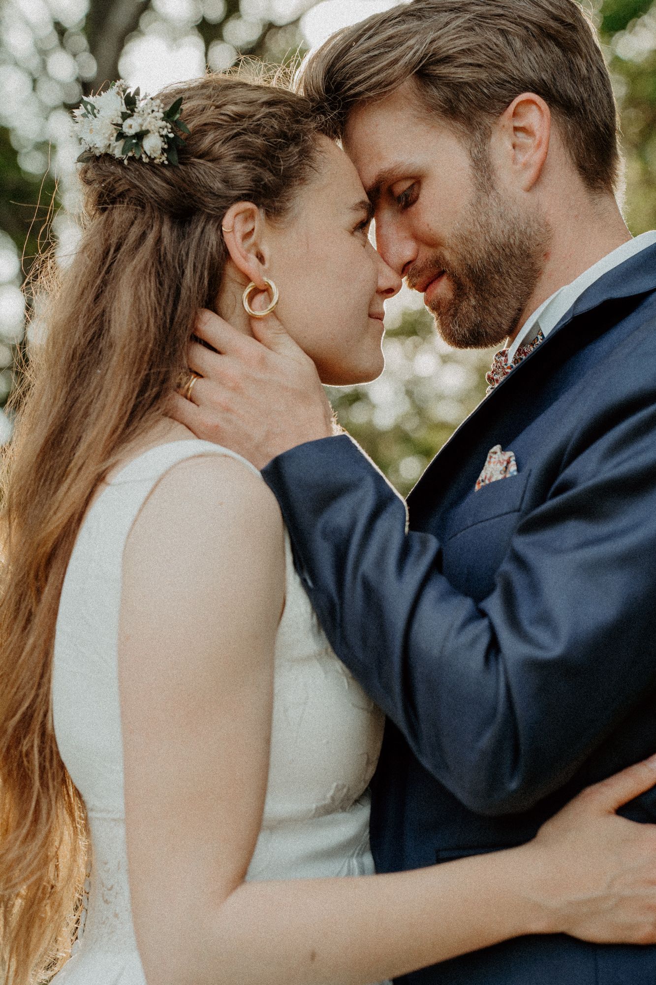 Close-up of a bride and groom tenderly touching foreheads in an intimate outdoor wedding portrait.