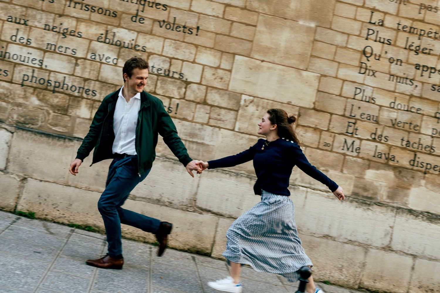Couple courant main dans la main le long d'un mur