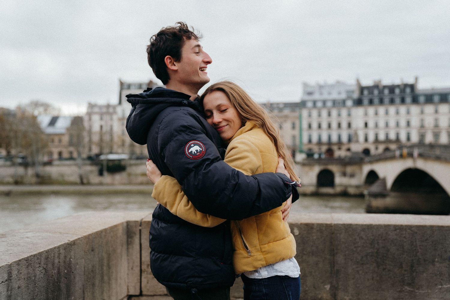 Couple souriant enlacé sur un pont parisien