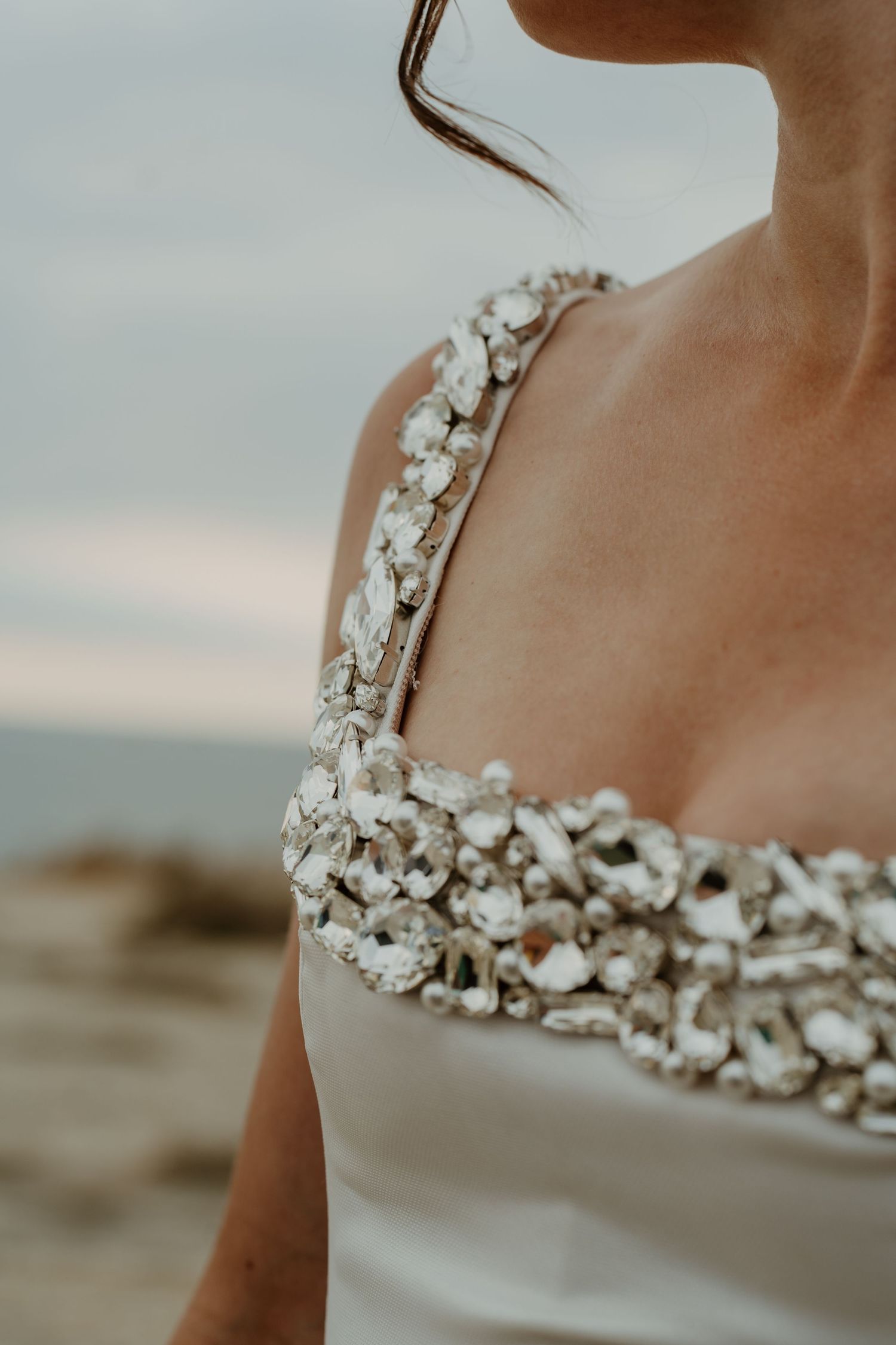 Détail d'une robe de mariée ornée, en bord de mer