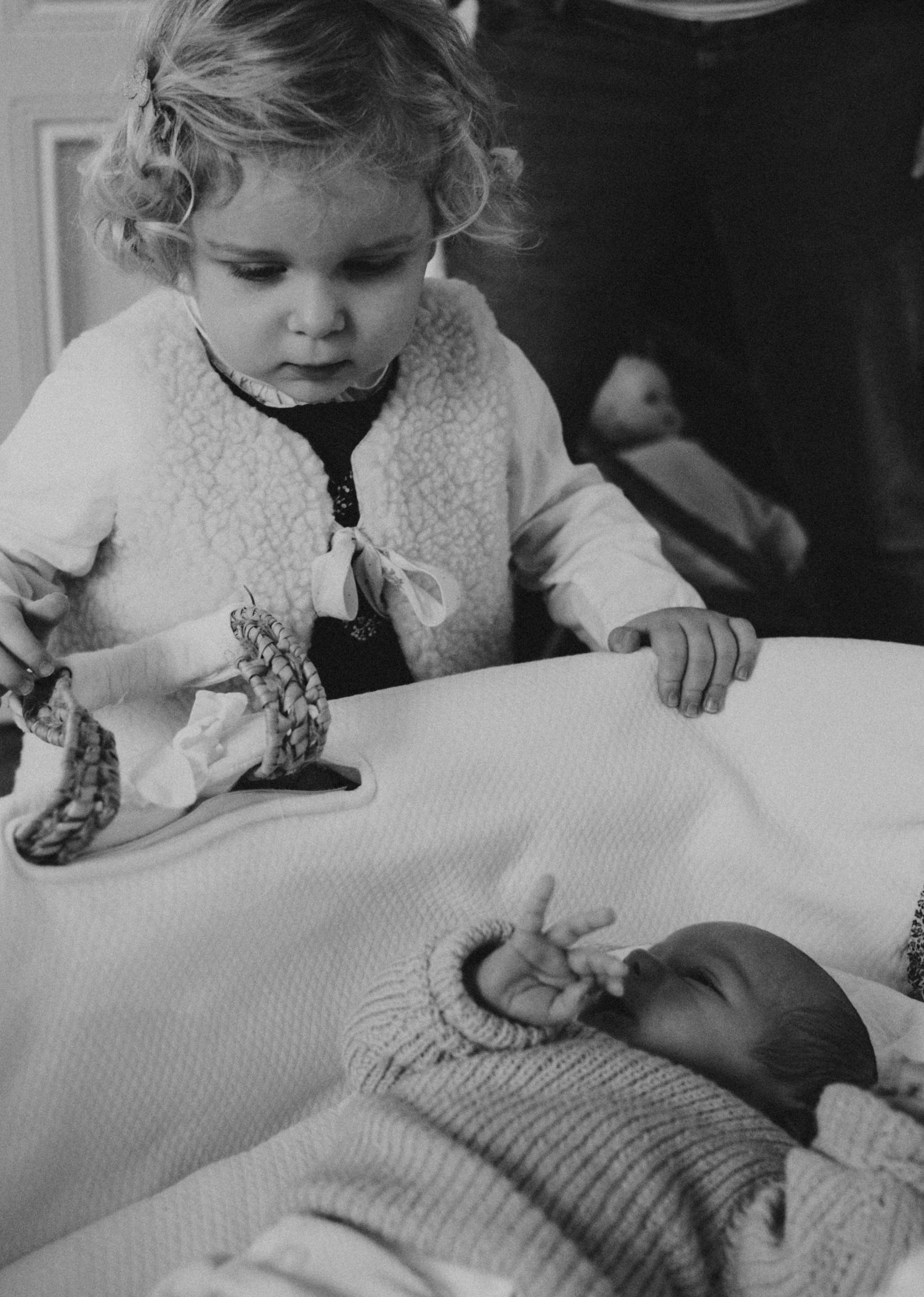 Grande sœur découvrant son nouveau-né frère, noir et blanc