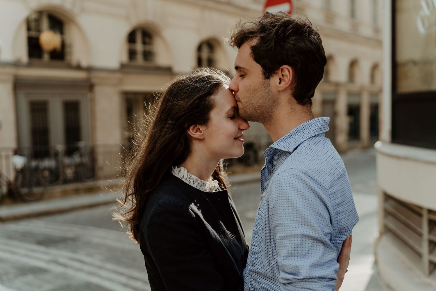 Couple sharing an intimate moment on a classic Parisian street backdrop.