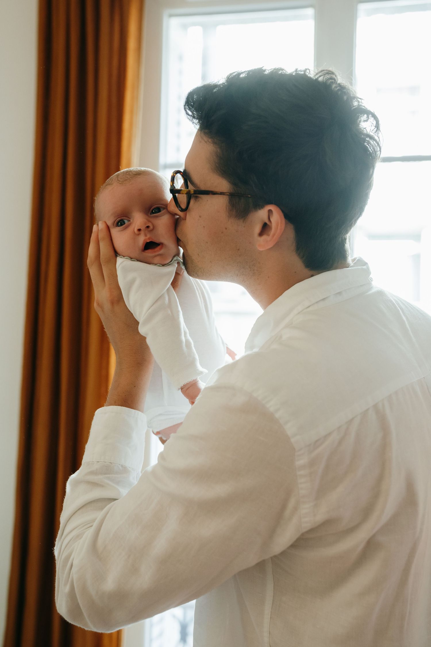 Père embrassant son bébé près d'une fenêtre