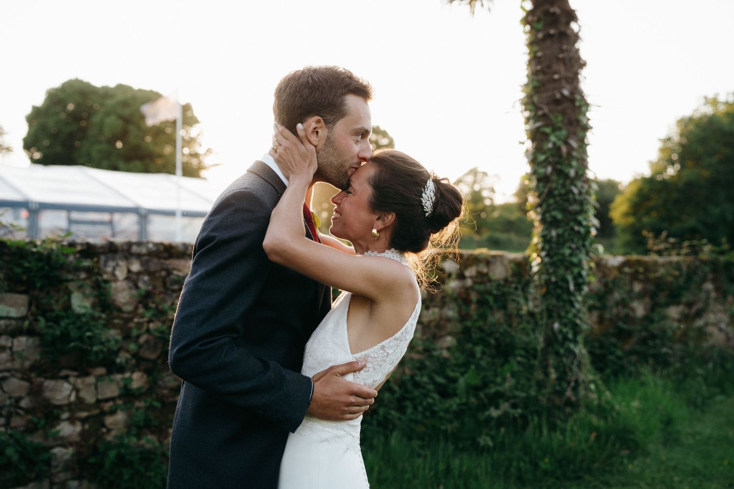 Mariés s'embrassant devant un mur en pierre, mariage à la Trinité-sur-Mer