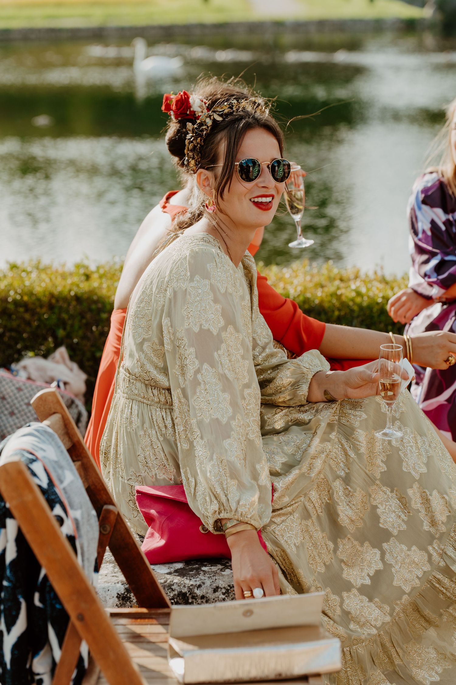 Invitée en robe dorée et lunettes de soleil assise dans le parc du château