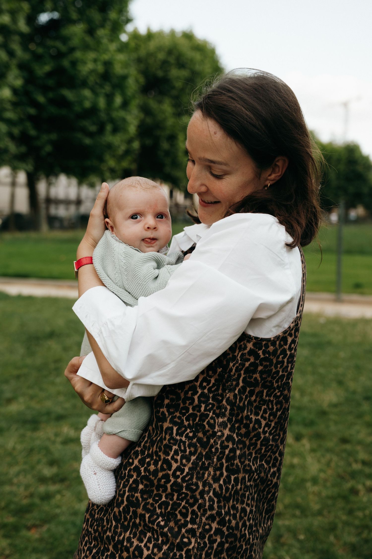 Mère souriante tenant son nouveau-né en extérieur
