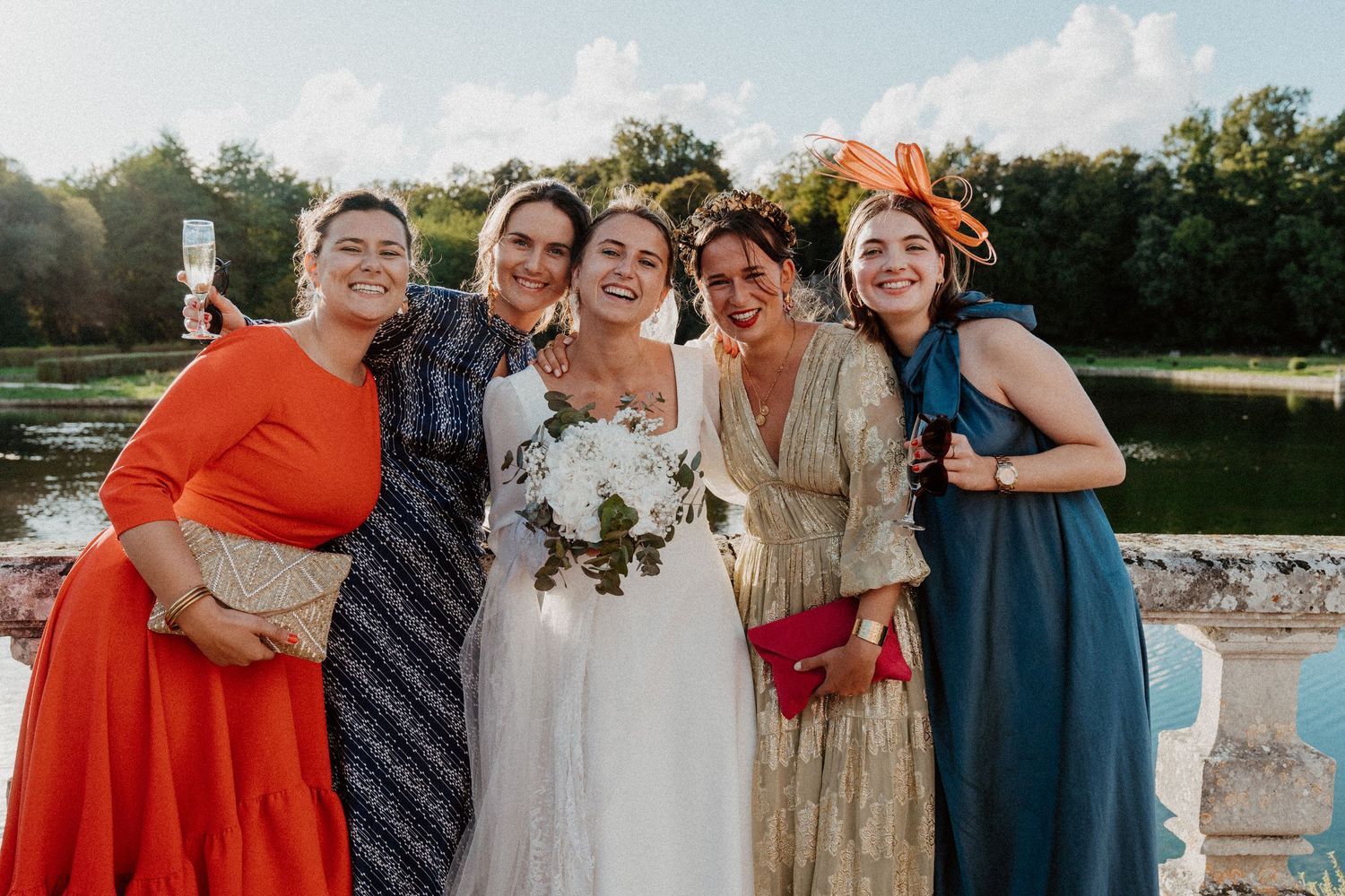 Groupe d'amies entourant la mariée et son bouquet sur la terrasse du château