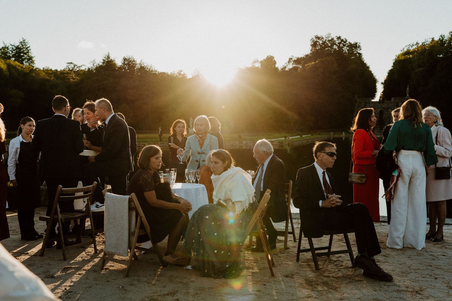 Invités réunis autour des tables hautes au coucher du soleil