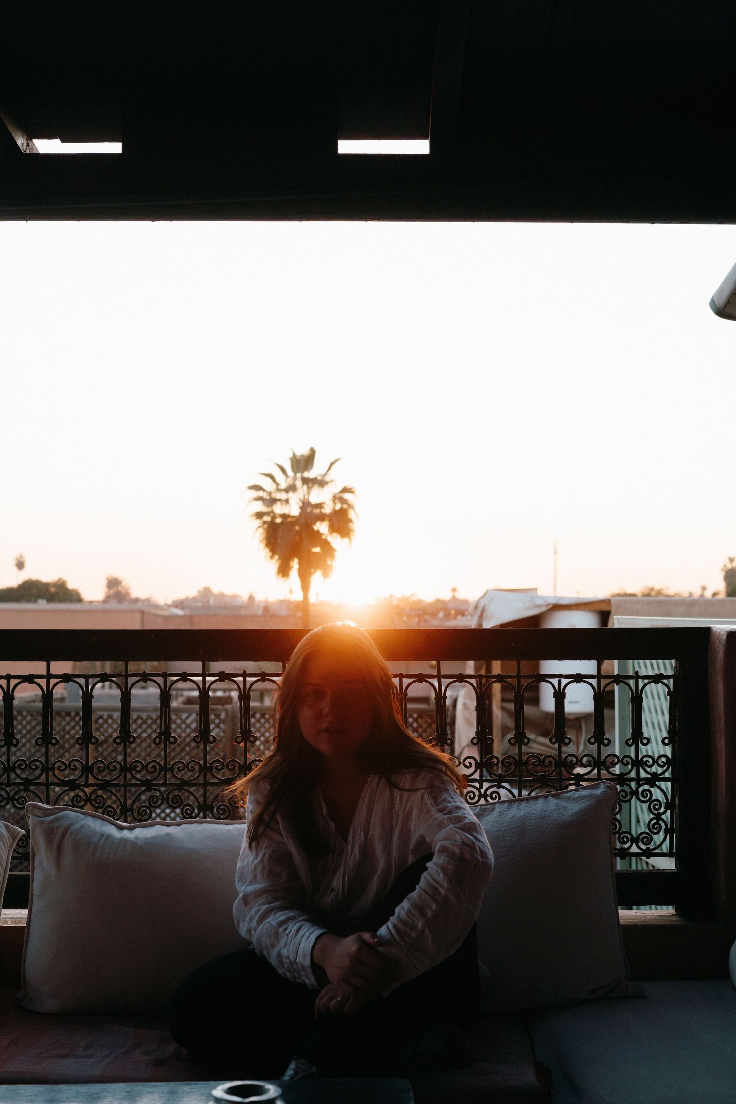 Femme assise sur un balcon au coucher du soleil
