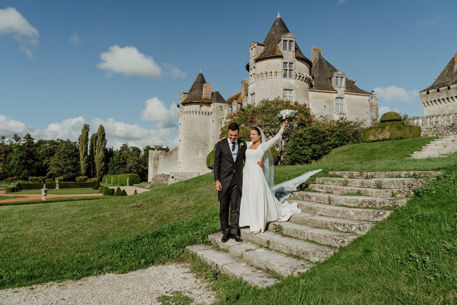 Mariés sur les marches d'un château, tourelles en arrière-plan