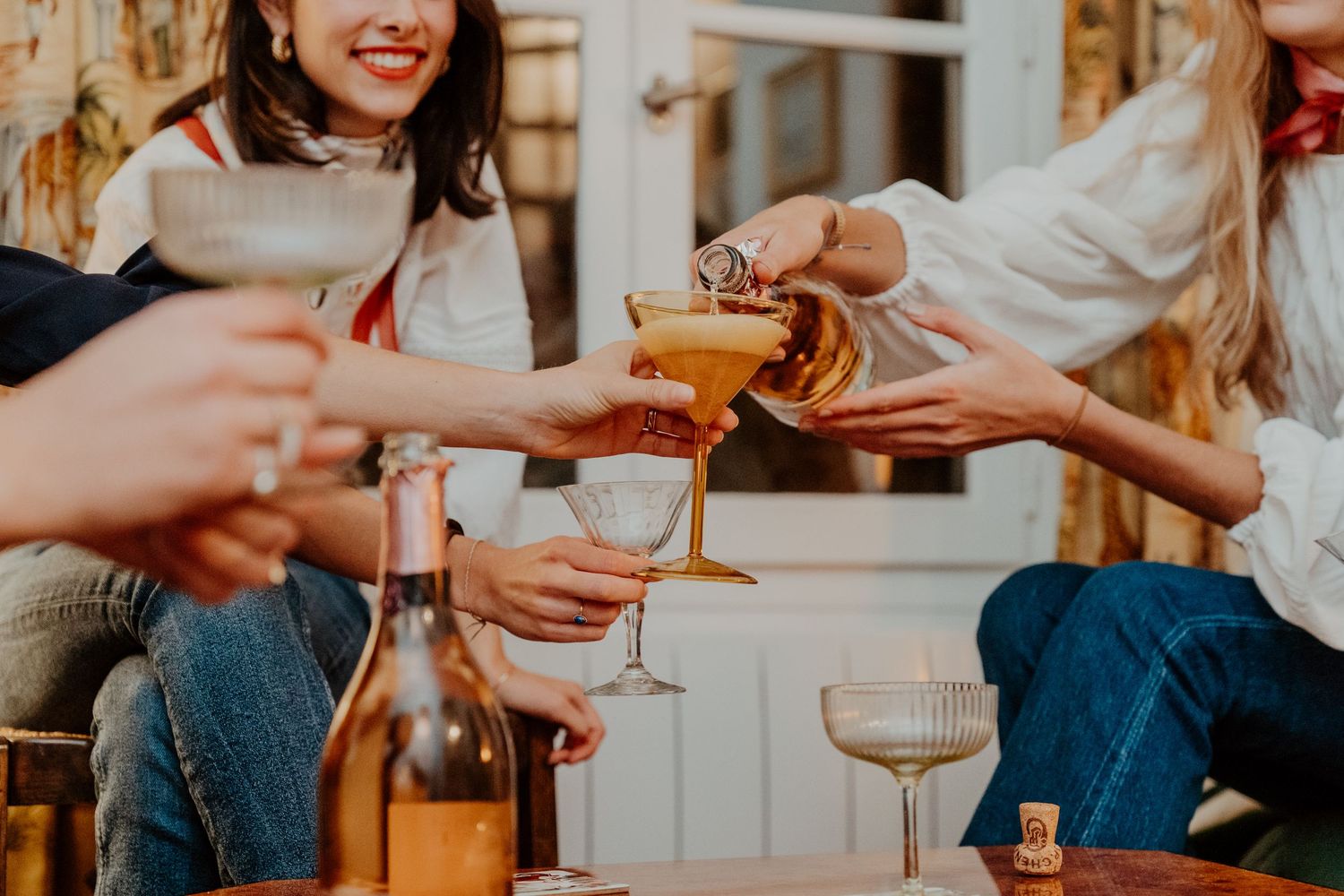 Group of women toasting cocktails and wine at outdoor social gathering.