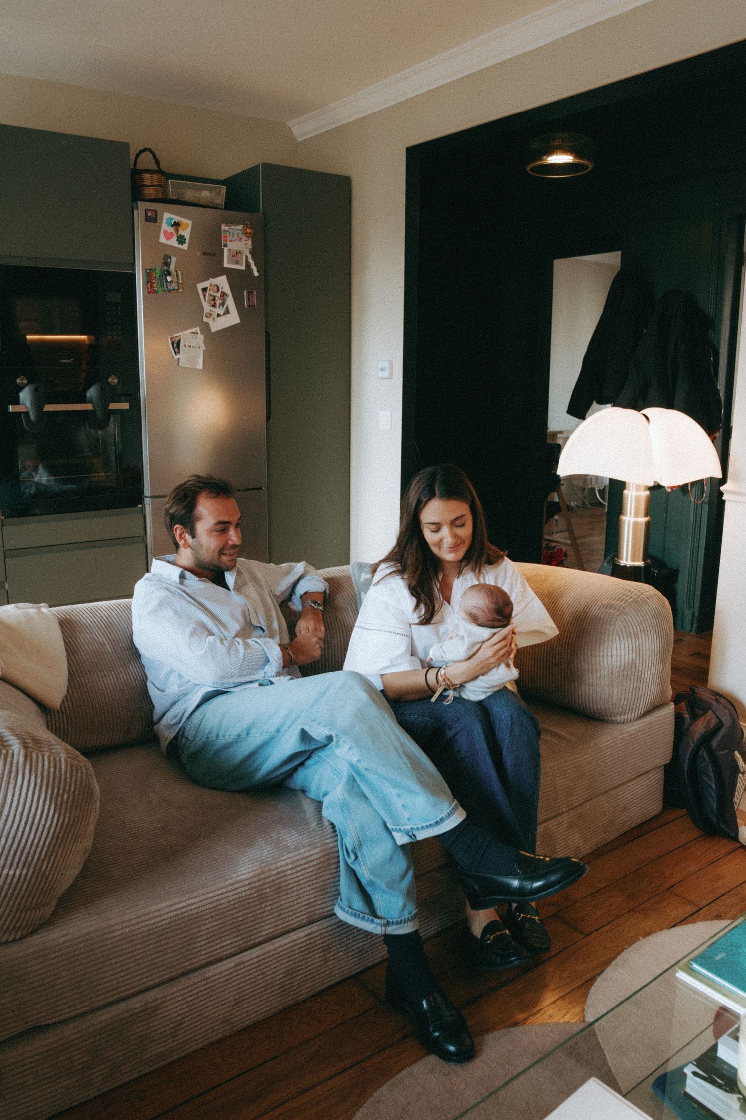 Jeunes parents sur un canapé, mère tenant le nouveau-né