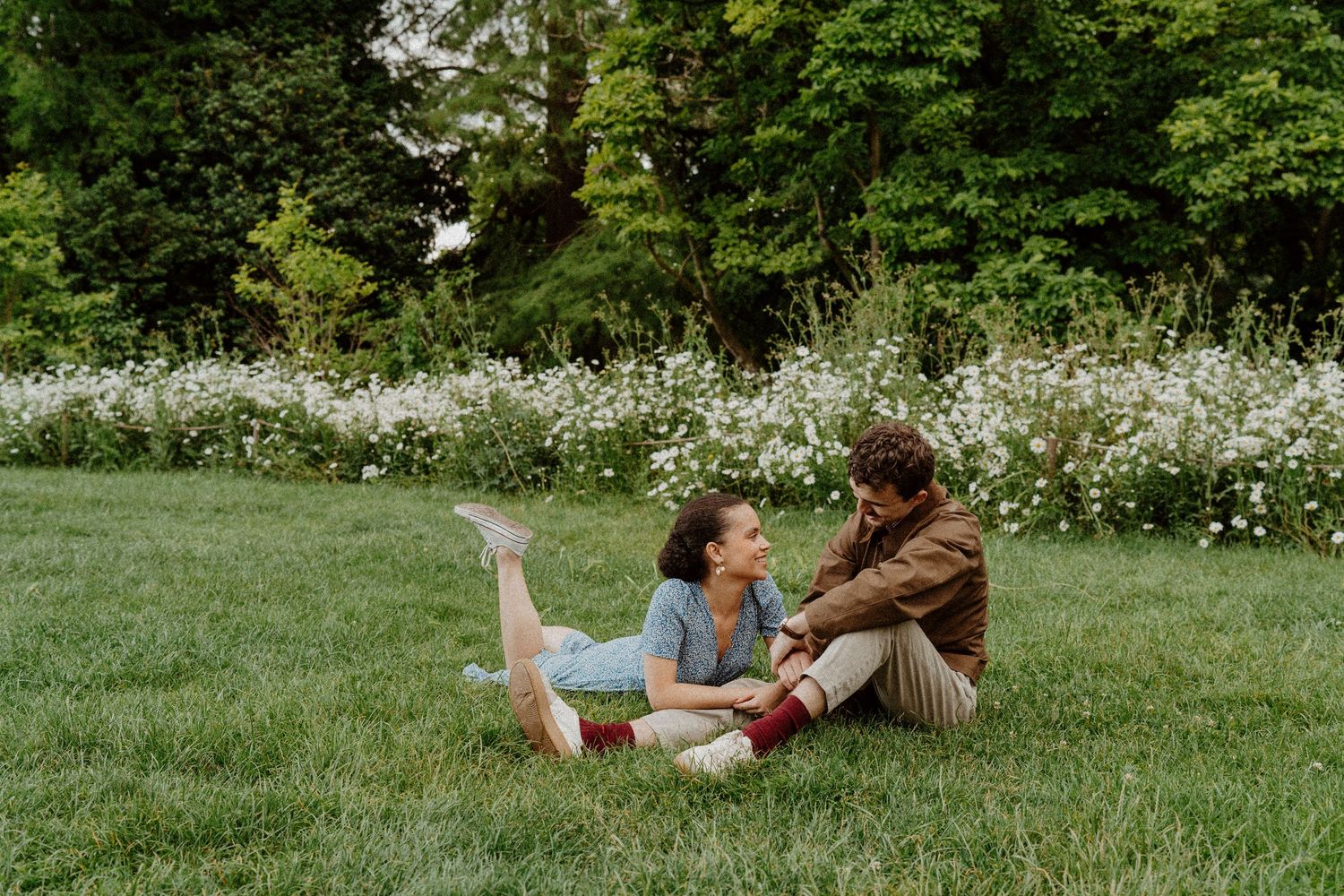 Couple assis dans l'herbe fleurie, moment complice