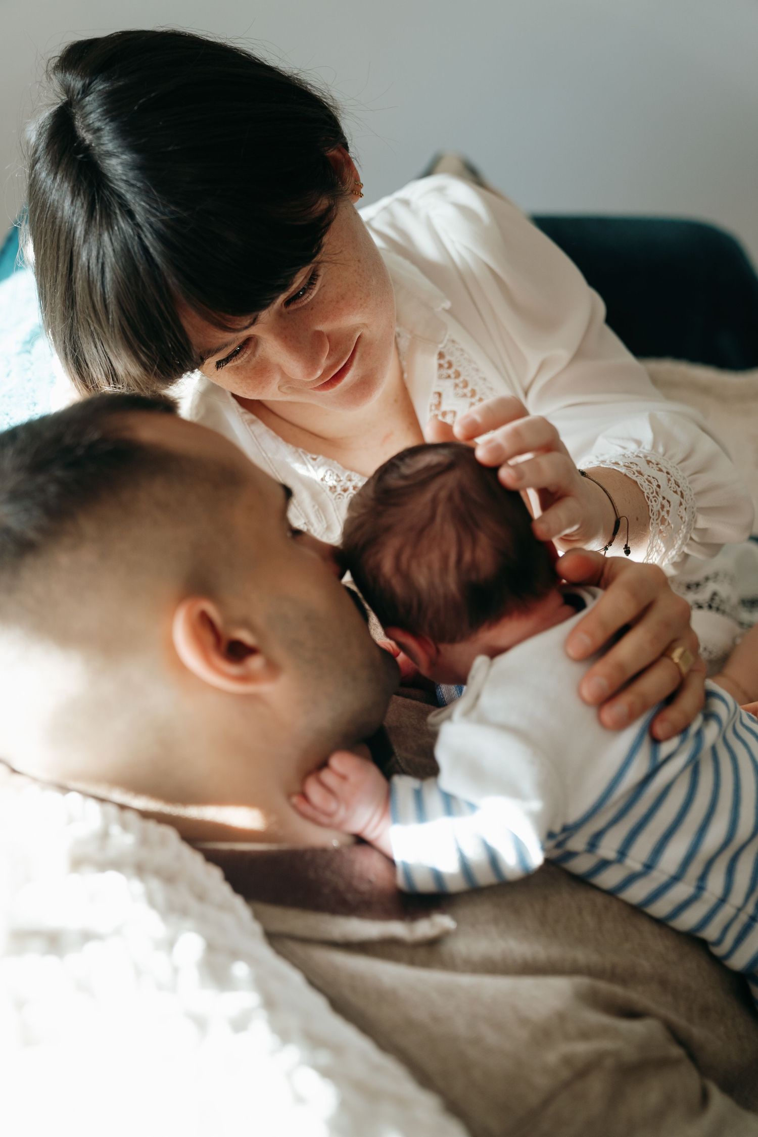 Père embrassant son nouveau-né, mère souriante à ses côtés