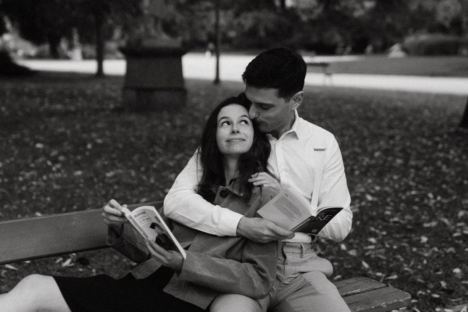 Couple assis sur un banc, lecture complice, noir et blanc