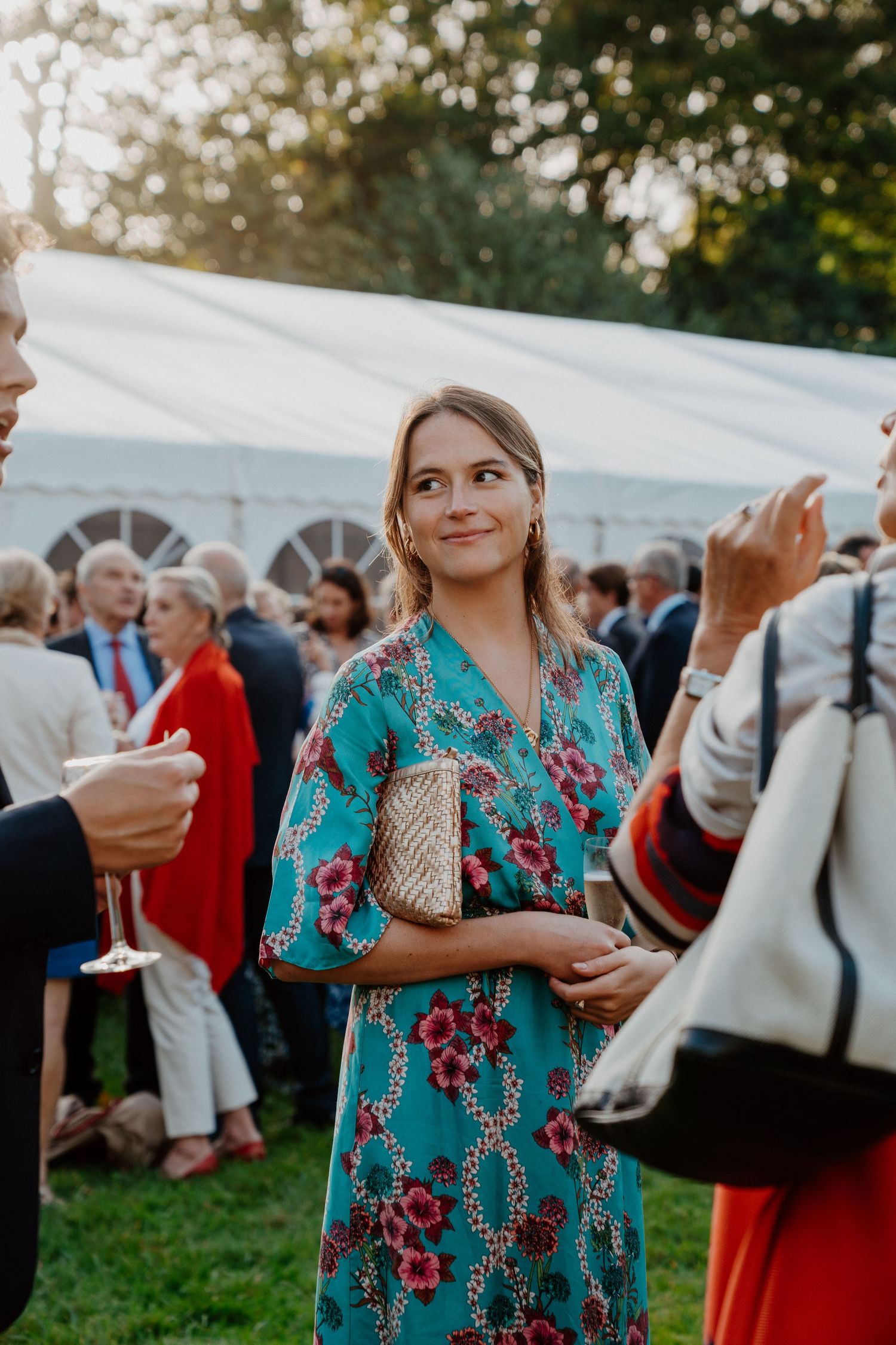 Invitée en robe fleurie devant la tente de réception pendant le cocktail