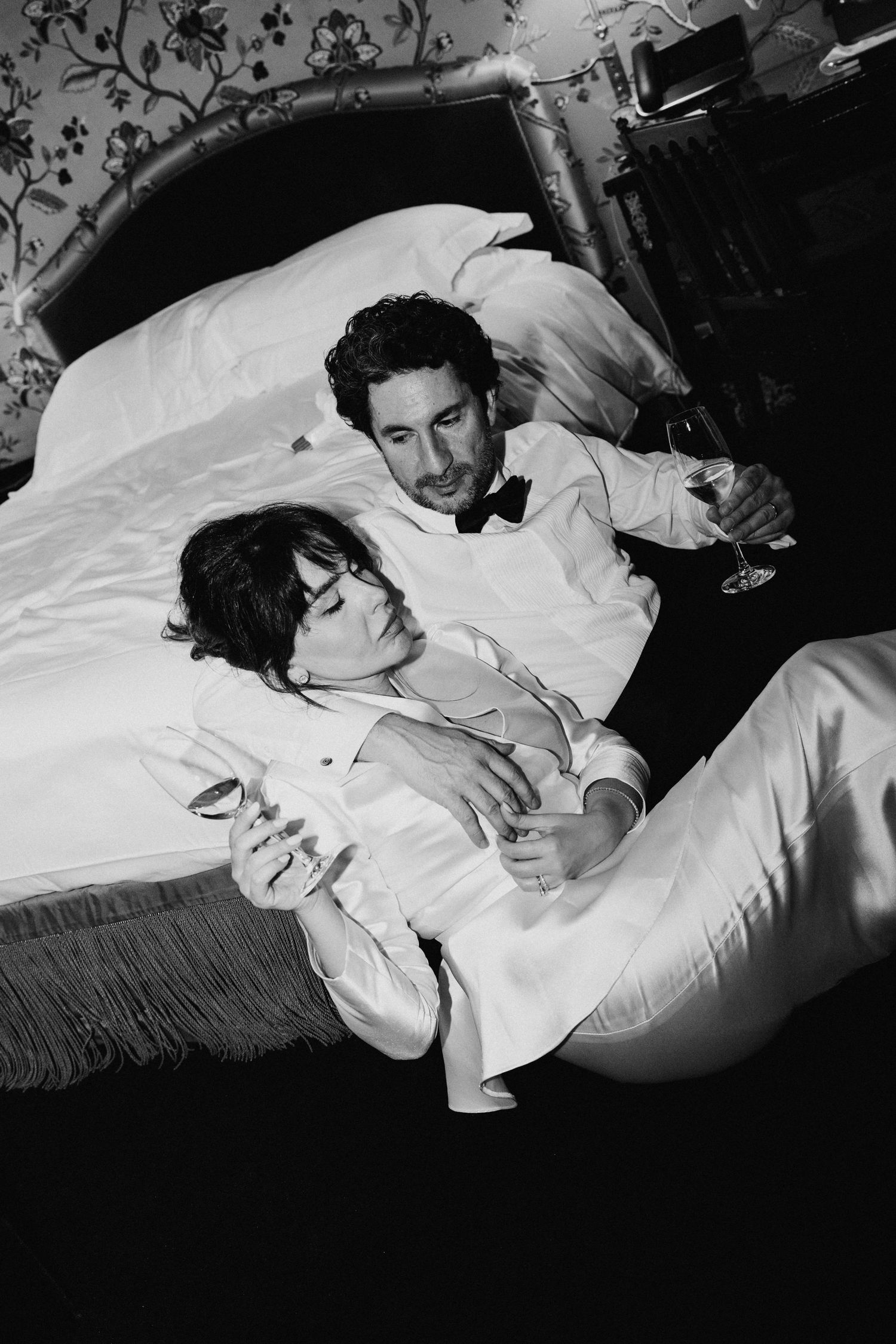 Mariés allongés en riant, photo de mariage en noir et blanc, champagne dans un hôtel parisien
