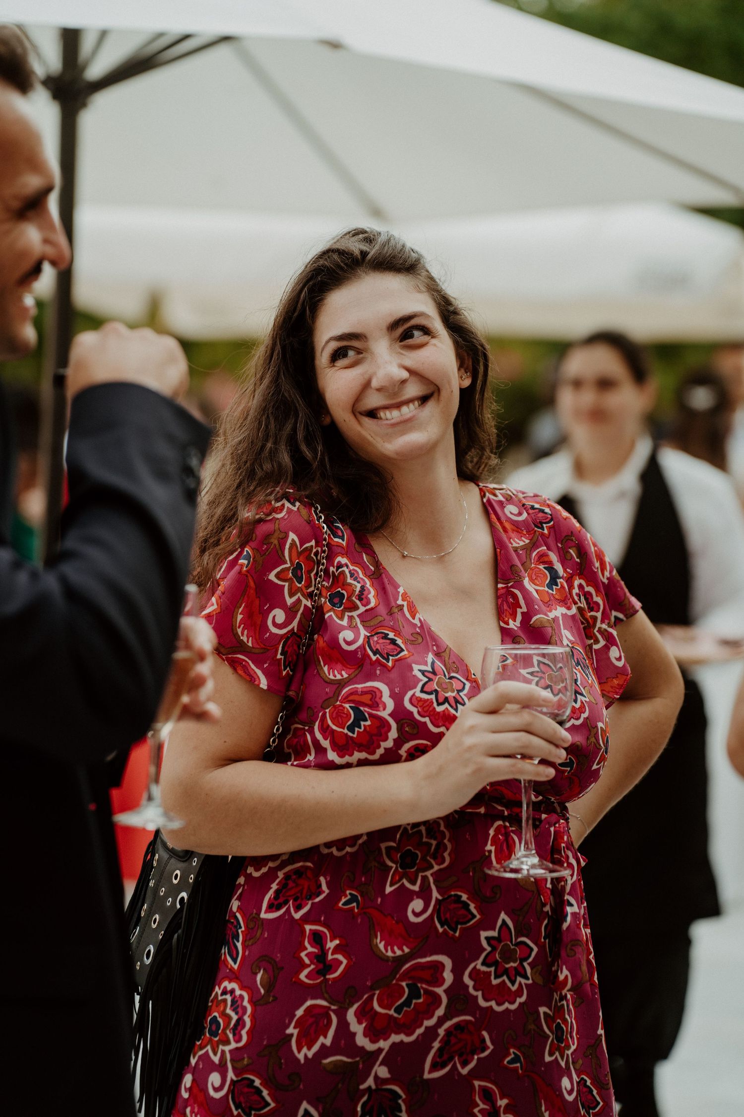 Invitée en robe rouge à motifs riant pendant le cocktail