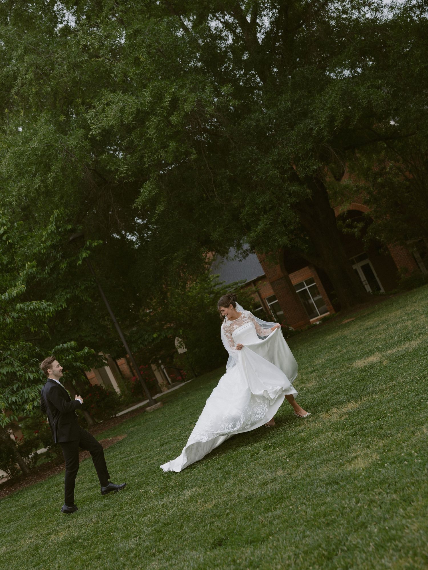 Bride and groom running together across a grassy field during their wedding day.