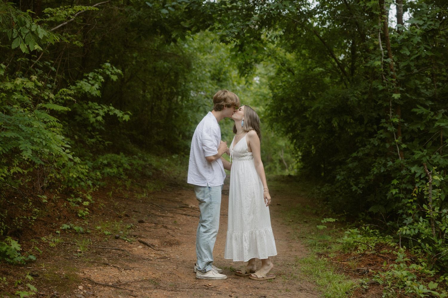 Couple sharing a quiet moment together on a wooded trail during an outdoor couple session.