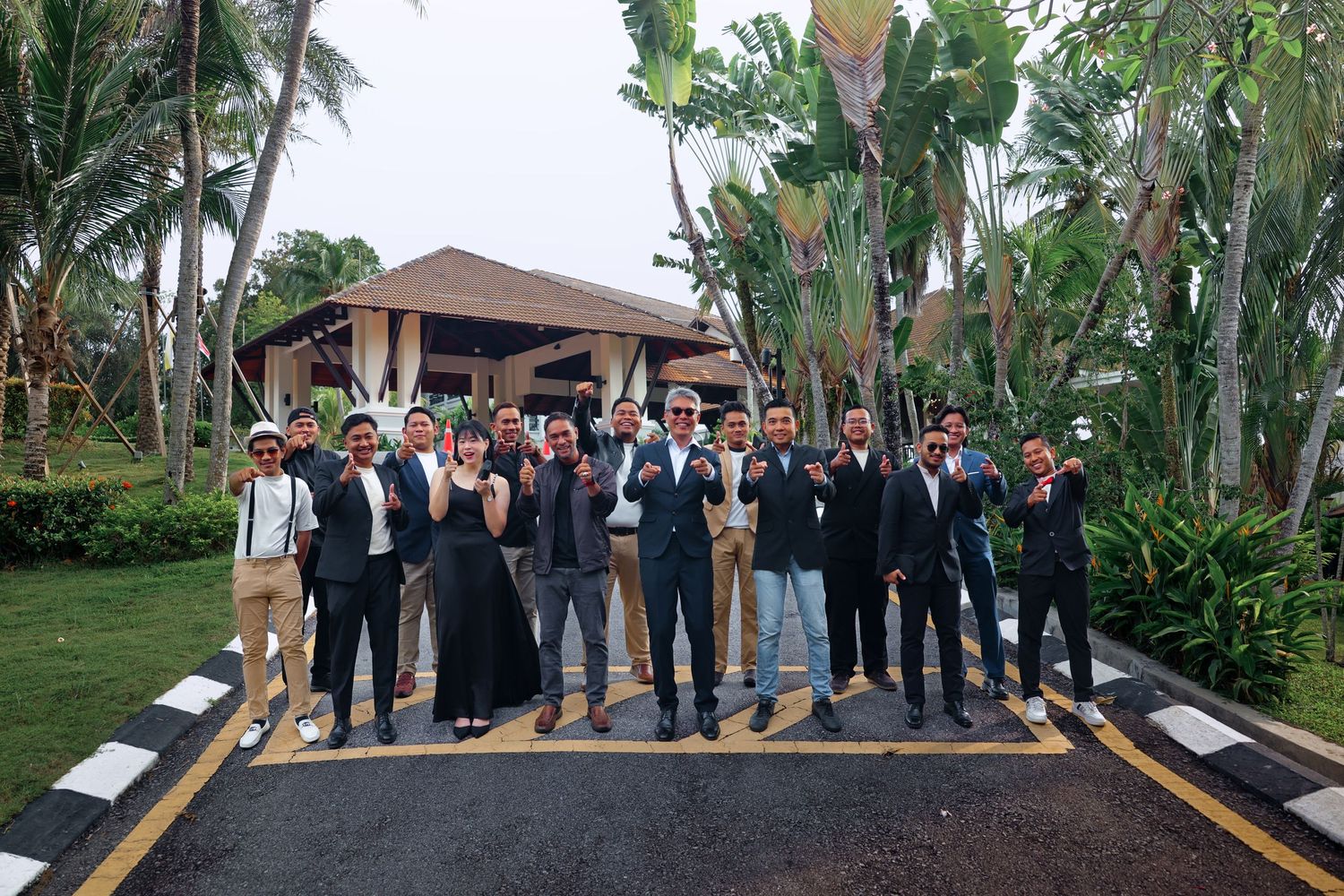 Group of professionals in business attire posing outdoors at a tropical resort with palm trees.