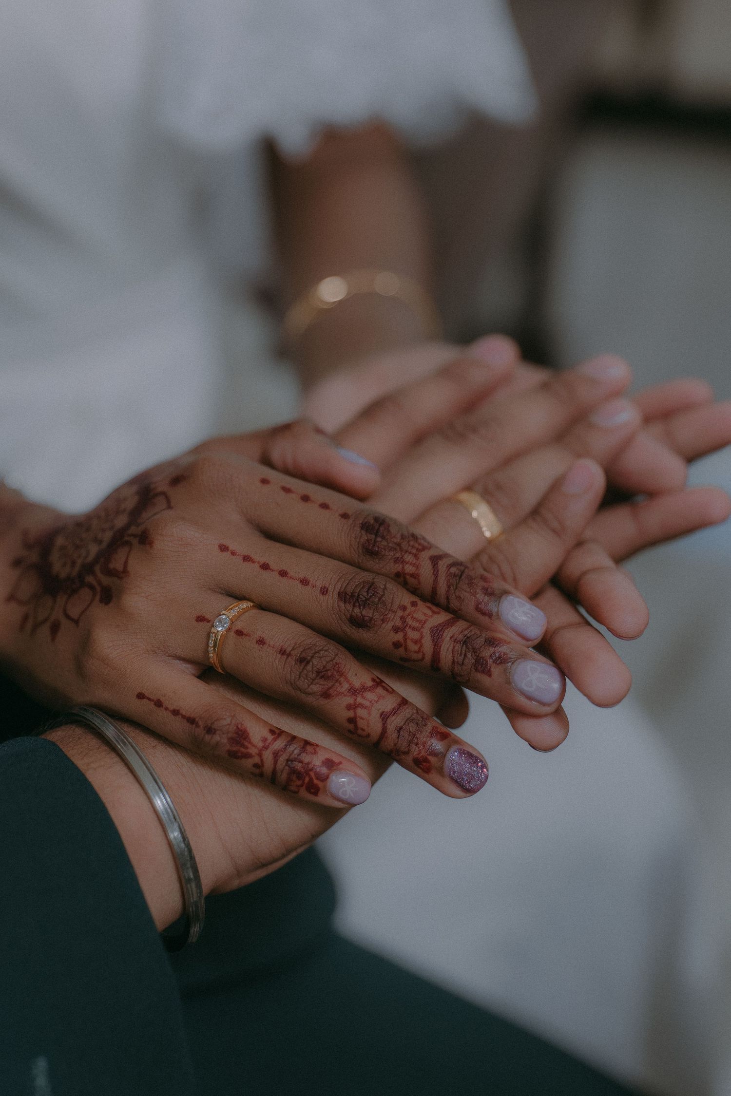 Close-up of hands adorned with intricate henna designs and wedding rings.