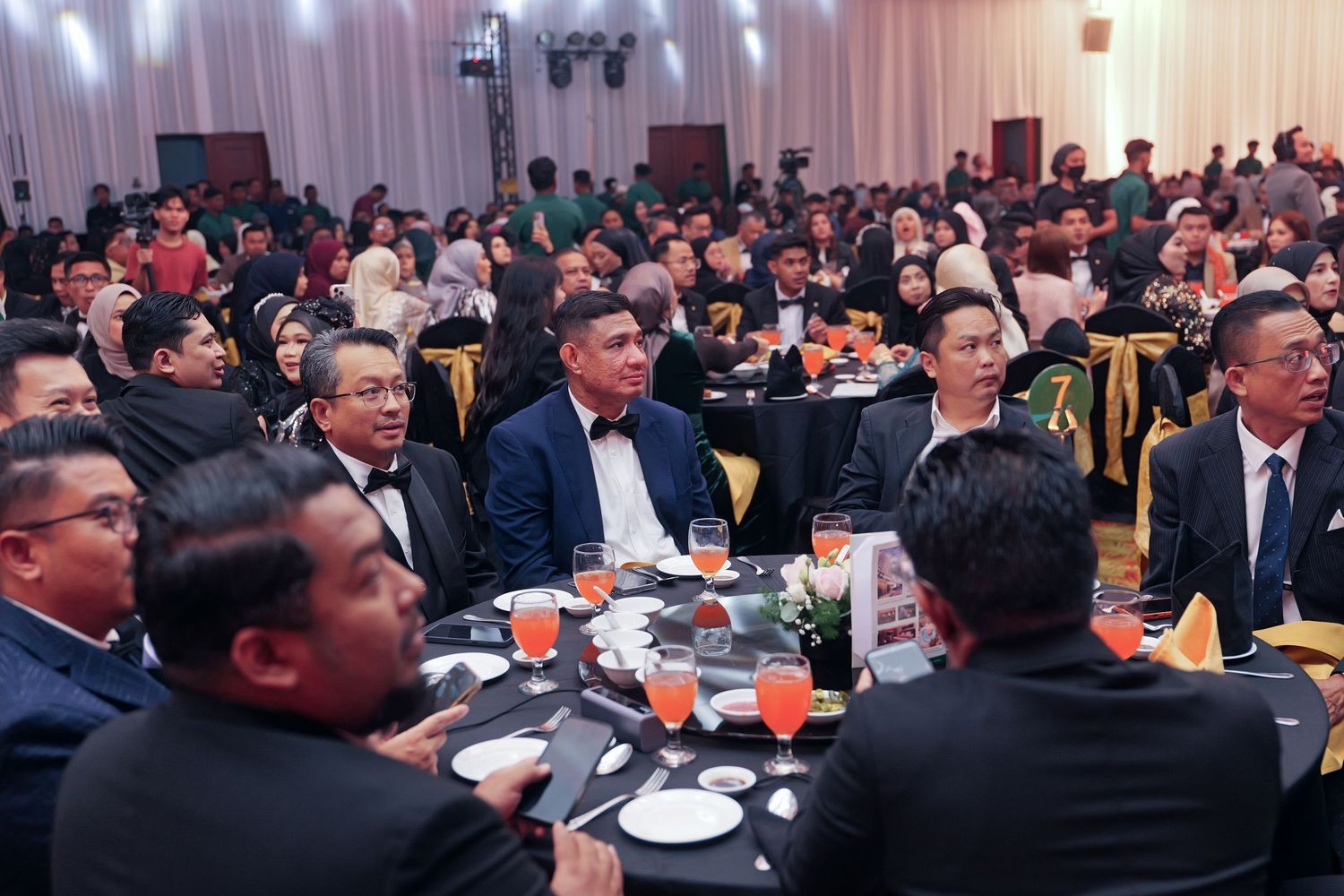 Large formal banquet hall filled with guests seated at round tables during an elegant corporate dinner event.